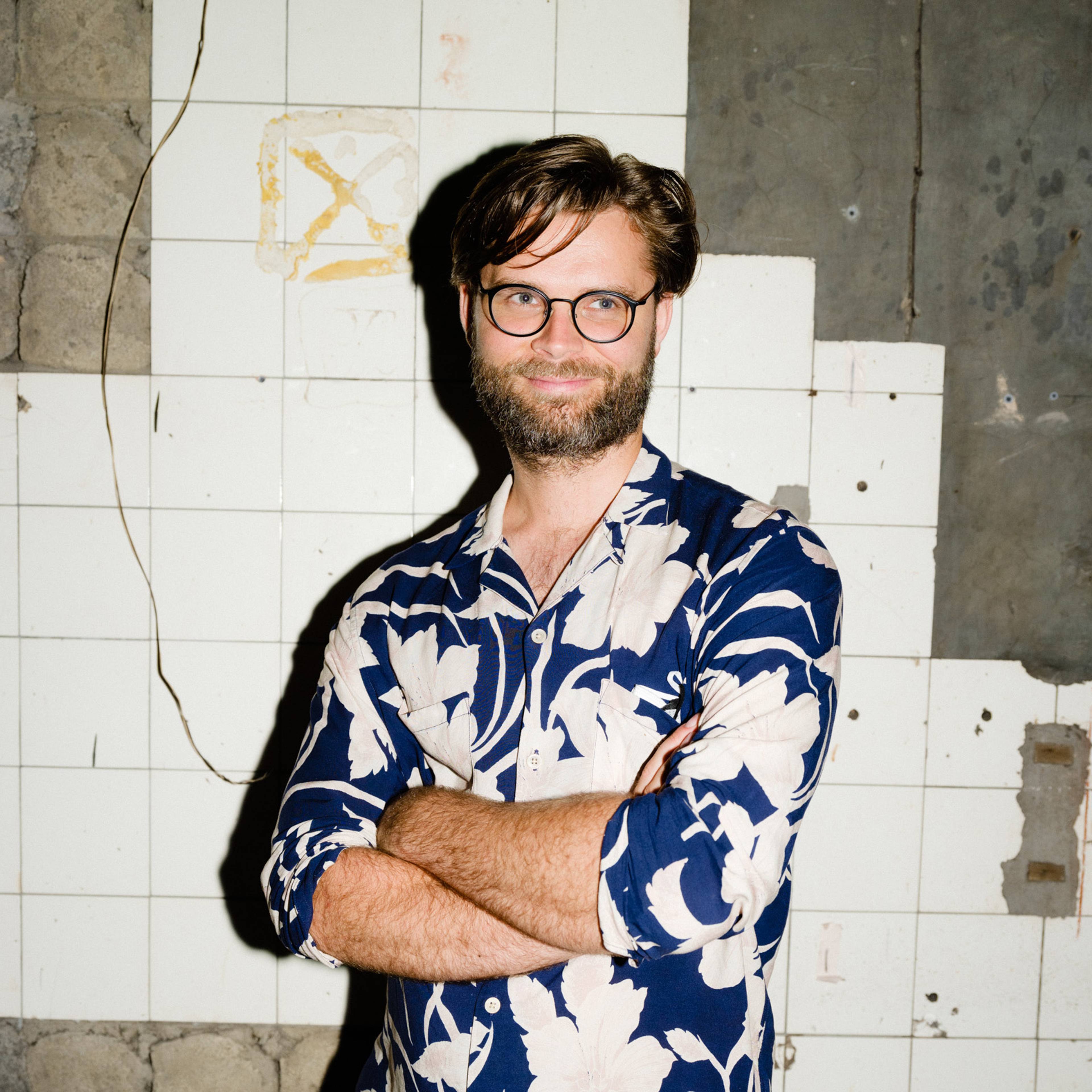 Portrait of artist Jakub Kudsk Steensen smiling with crossed arms.