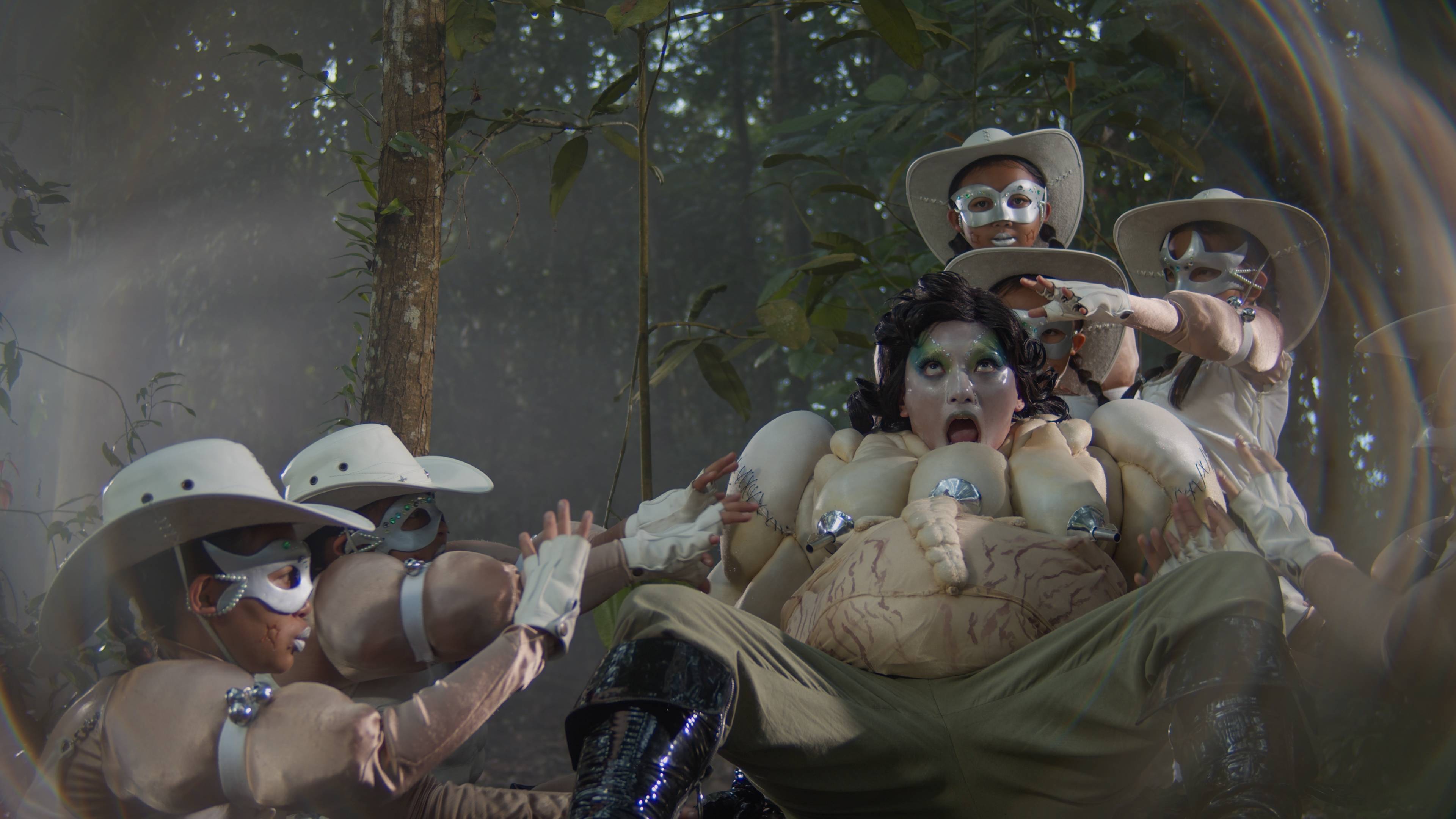 Red-and-black illustration featuring a cloaked central figure, stylised faces, skulls and dense abstract patterns creating a dramatic, surreal atmosphere.