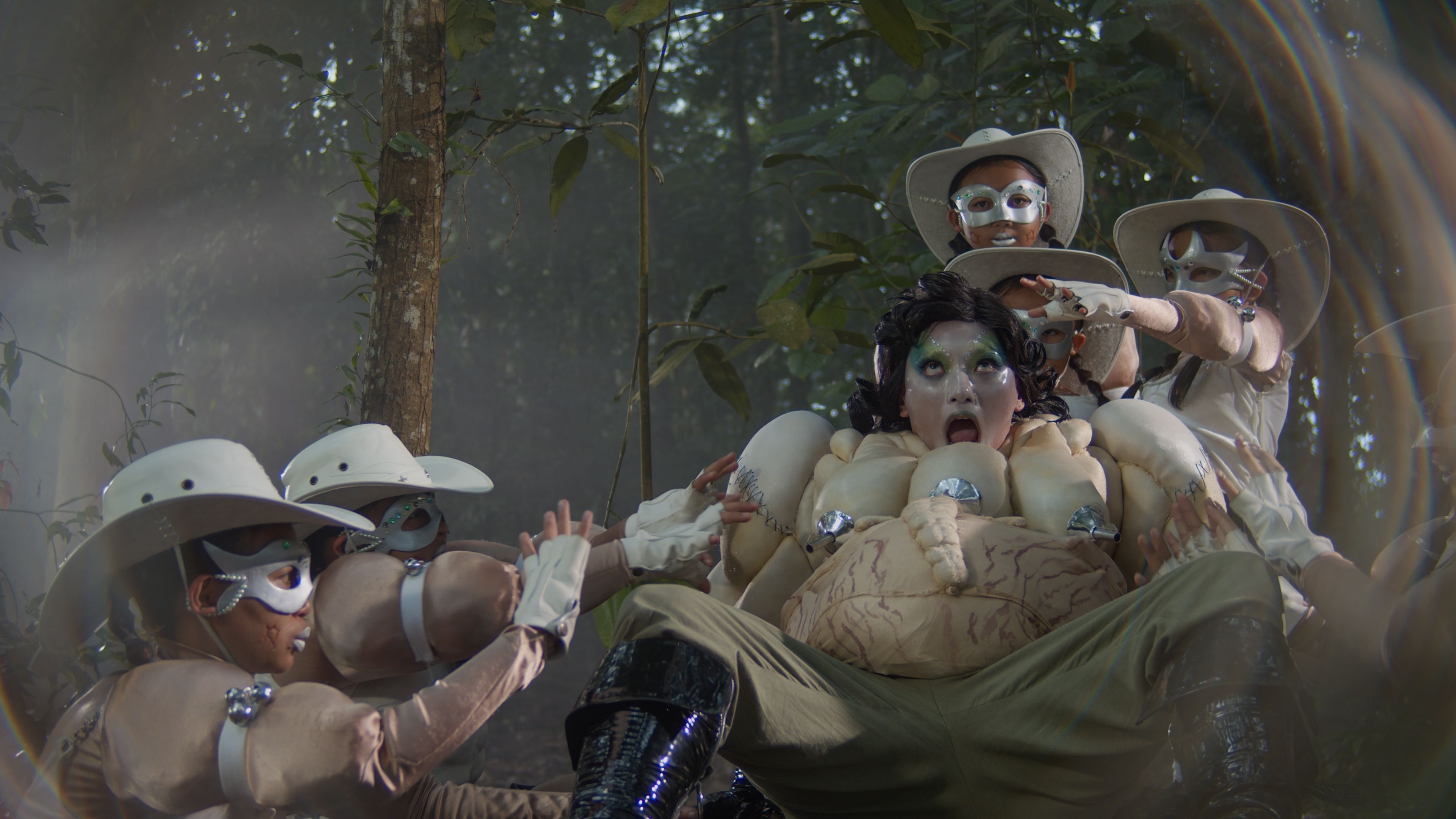 Red-and-black illustration featuring a cloaked central figure, stylised faces, skulls and dense abstract patterns creating a dramatic, surreal atmosphere.