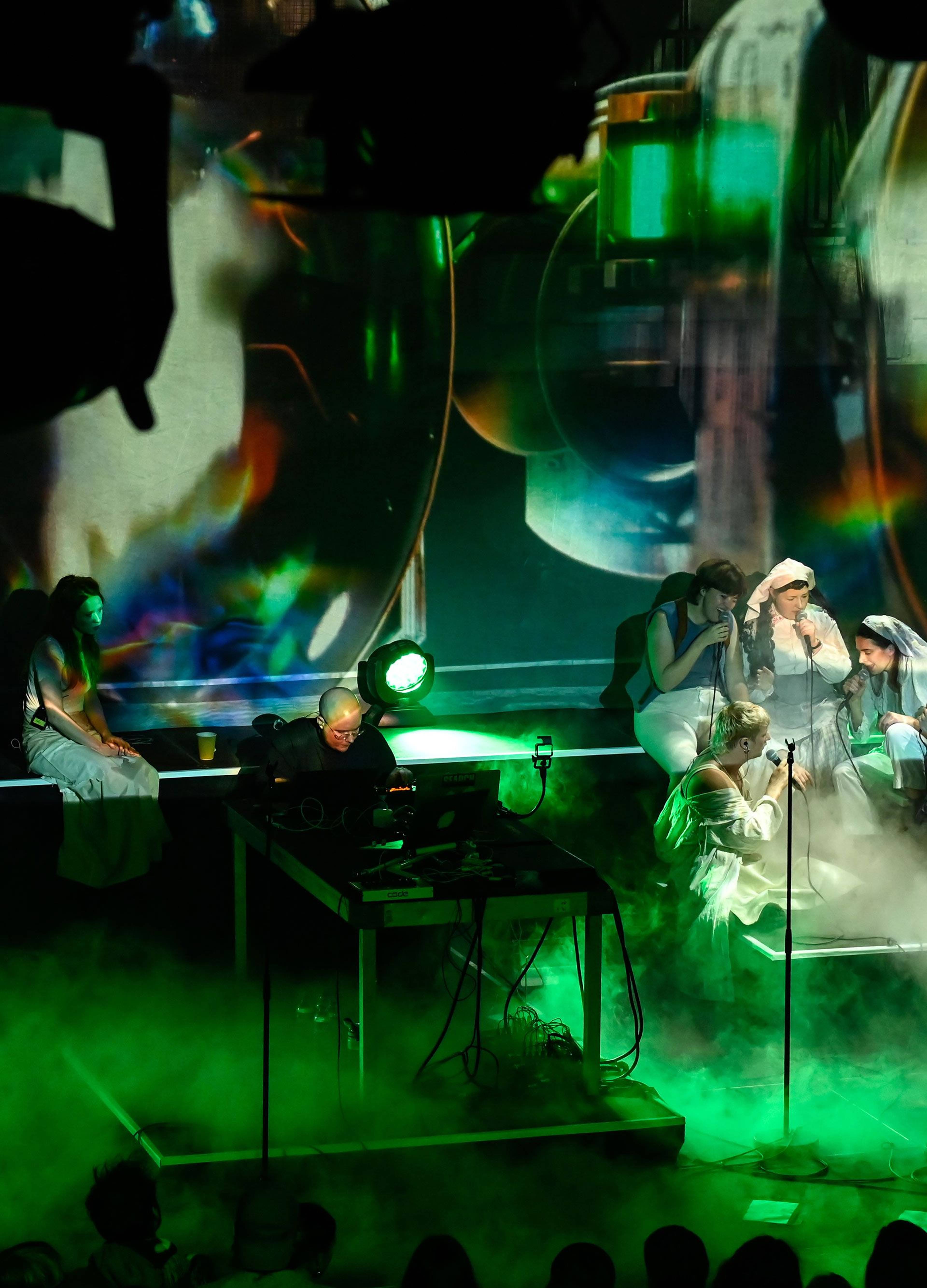 Performers onstage at Kraftwerk Berlin surrounded by green fog and digital projections.