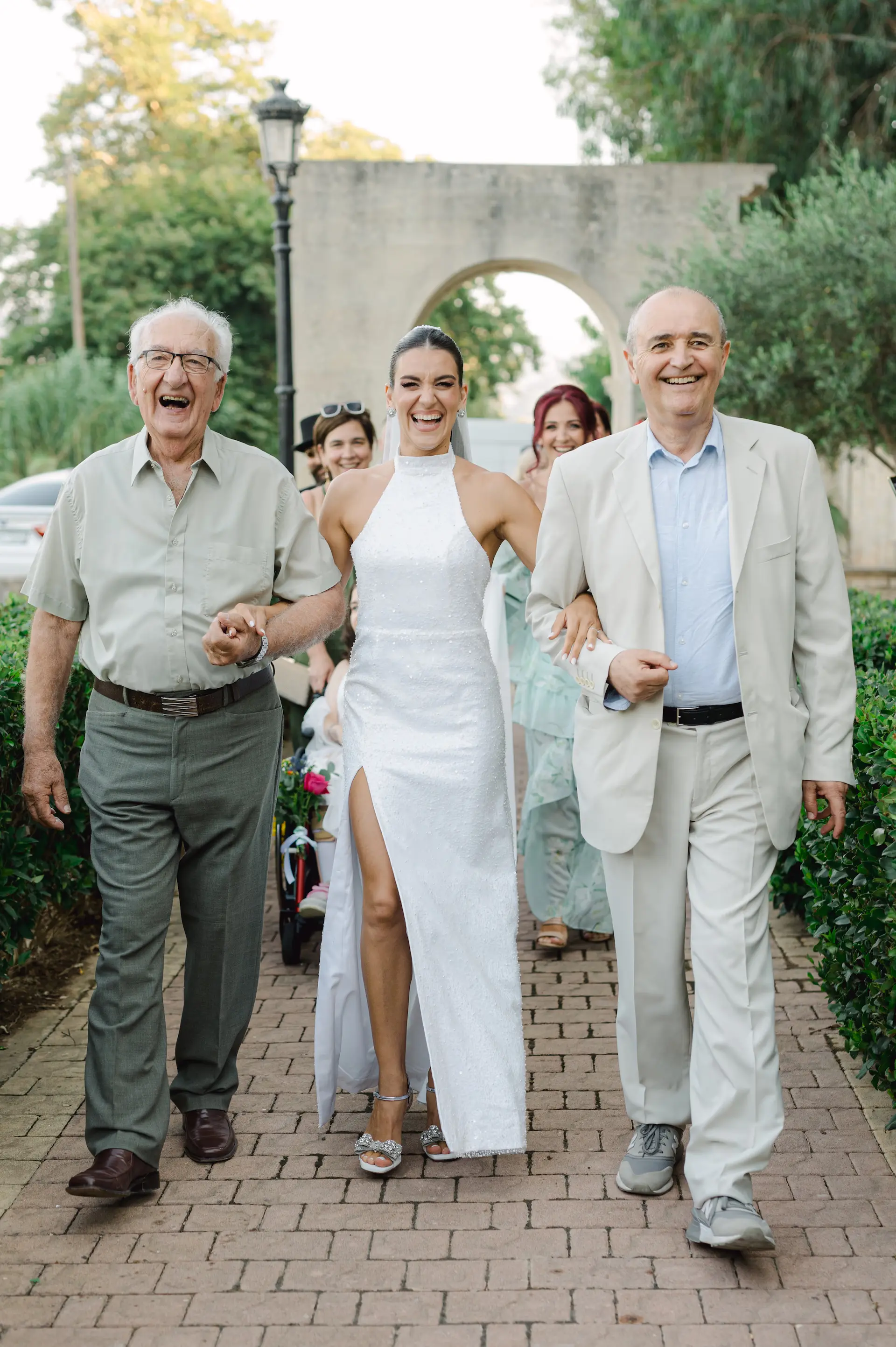 a woman in a white dress walking with a man in a suit and a woman in a white dress