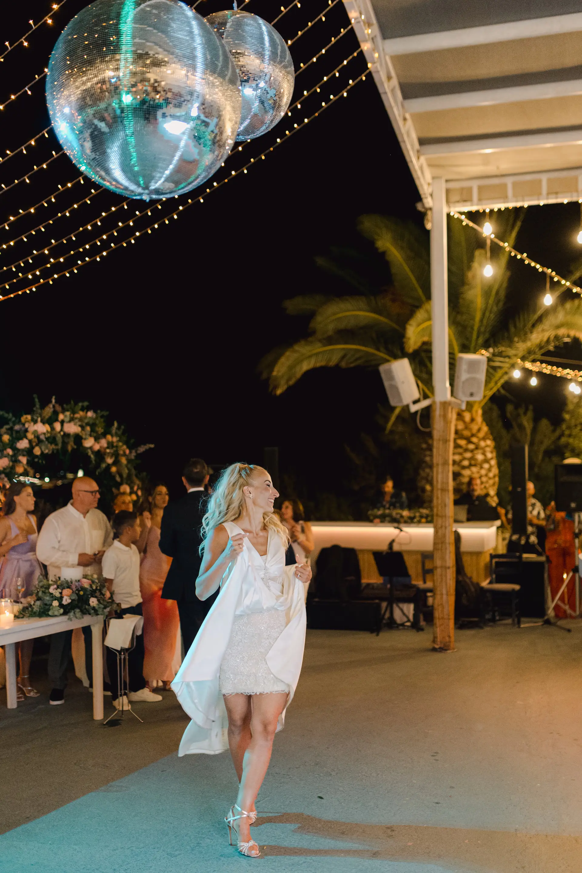 Bride dancing at night under disco ball decorations at her wedding in Crete.