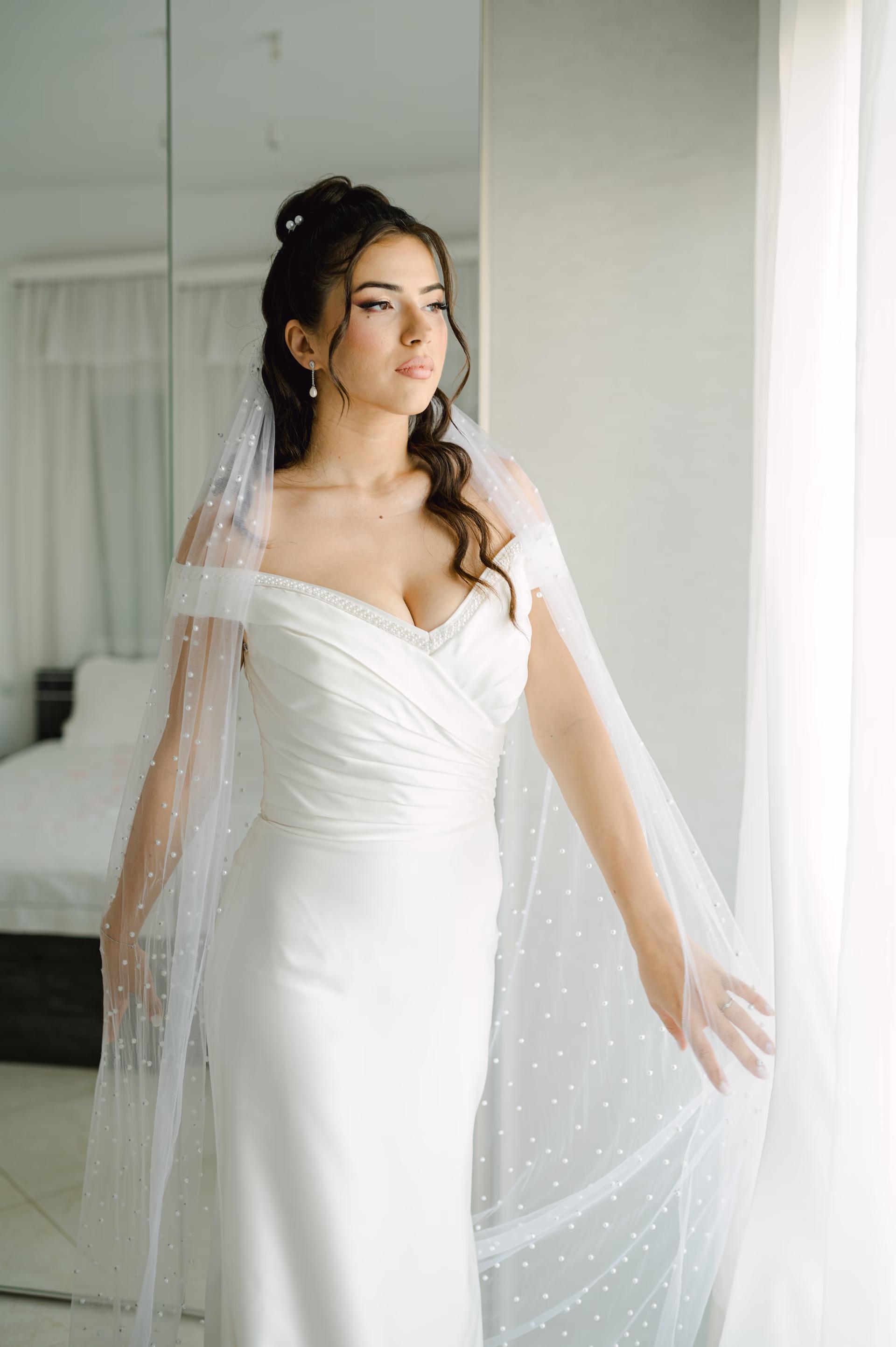 Elegant bridal portrait of a bride in a sophisticated white wedding dress with a sleek silhouette and minimalist styling.