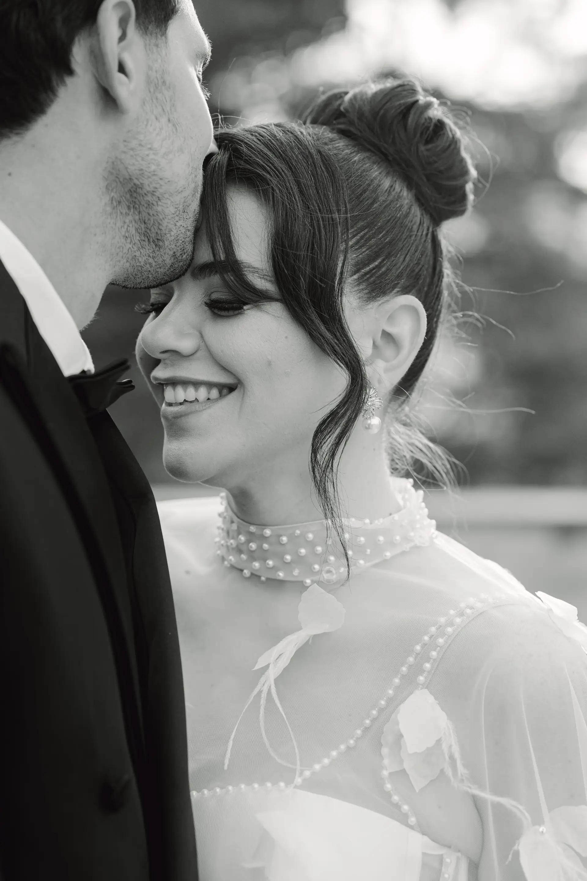 groom kissing bride's forehead in black and white