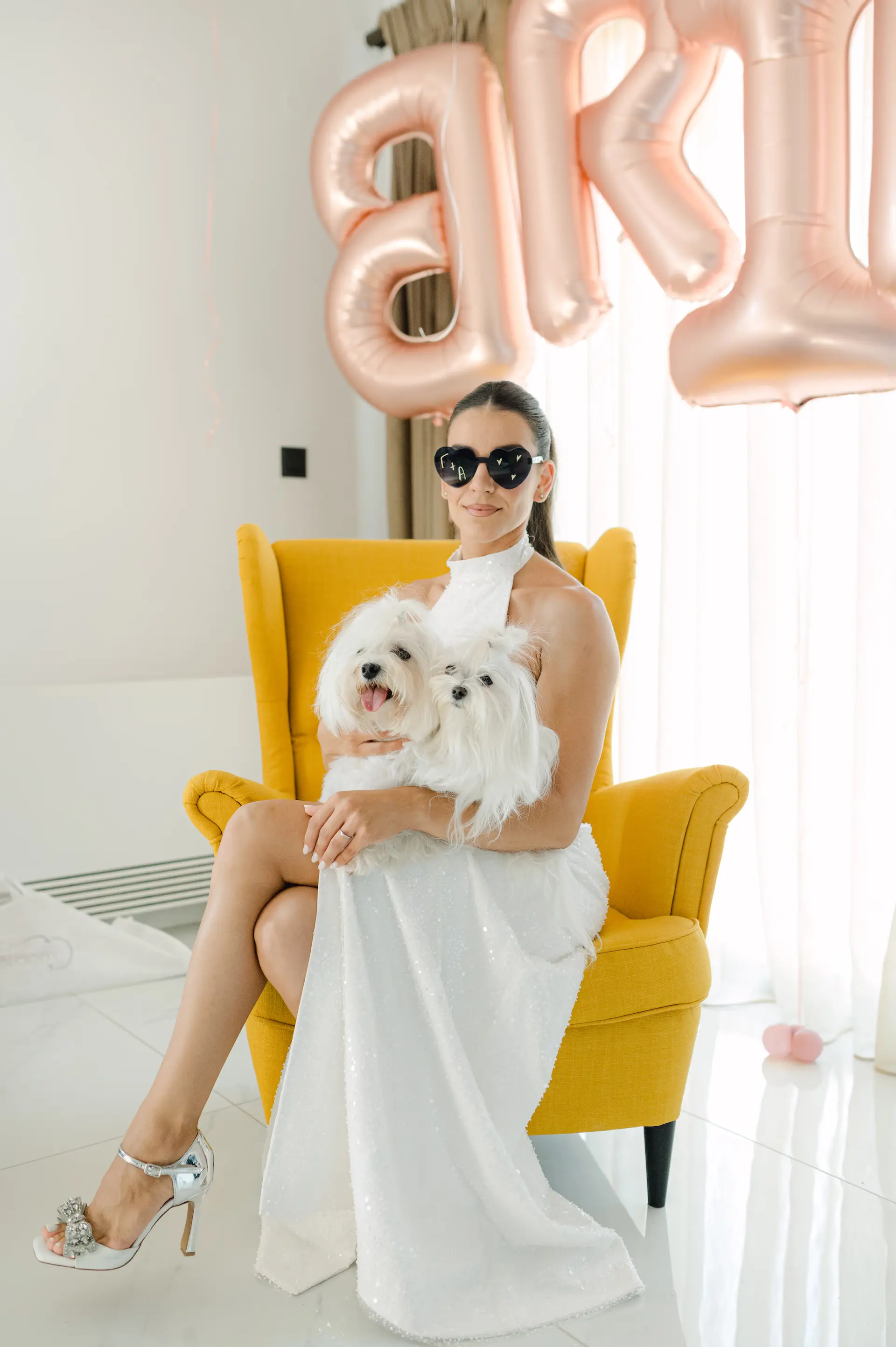 a woman in a white dress holding two dogs