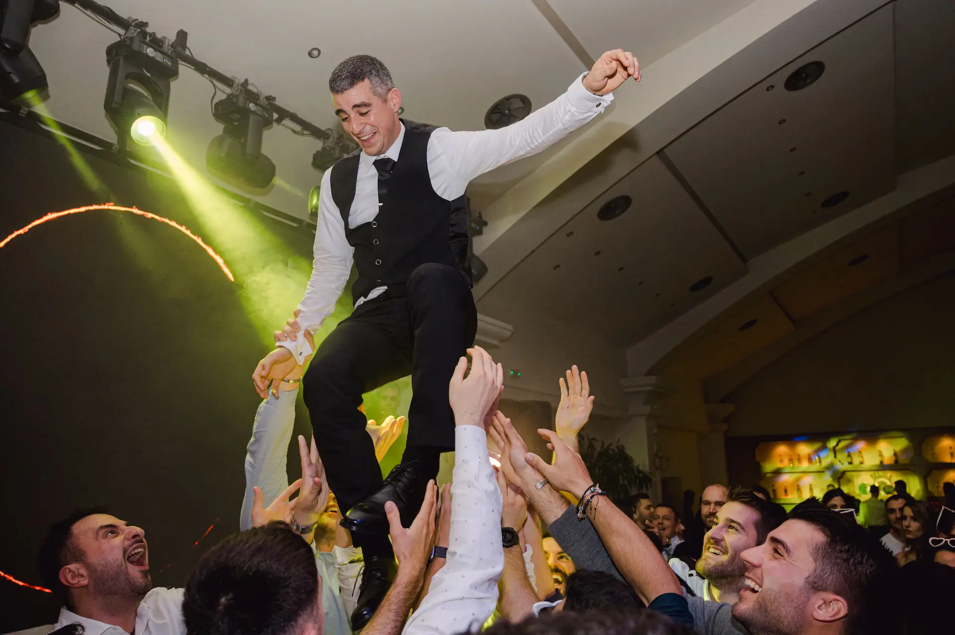 Exciting moment at the wedding party as cheering friends throw the groom into the air.