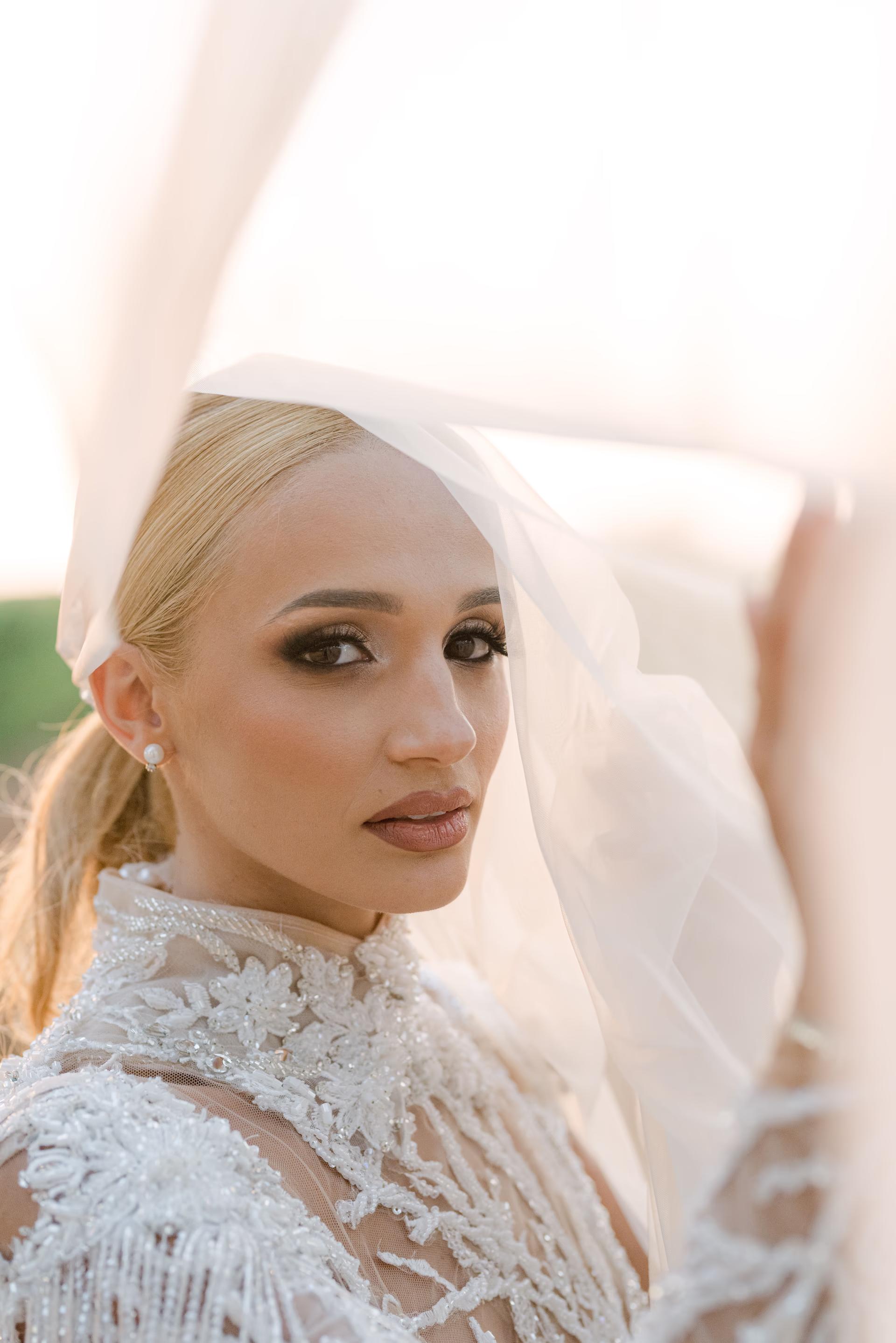 Soft-focus bridal portrait featuring a bride in a white gown with ethereal lighting and a natural makeup look.