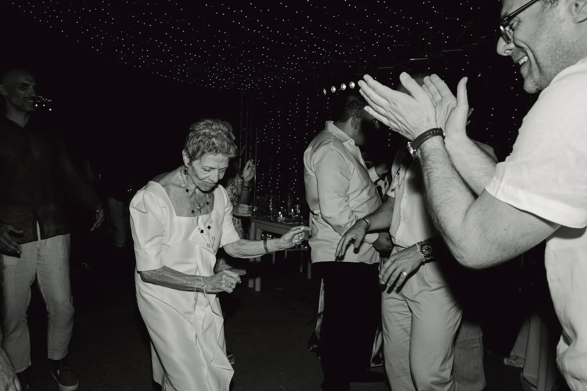 a woman in a white dress dancing next to a group of people