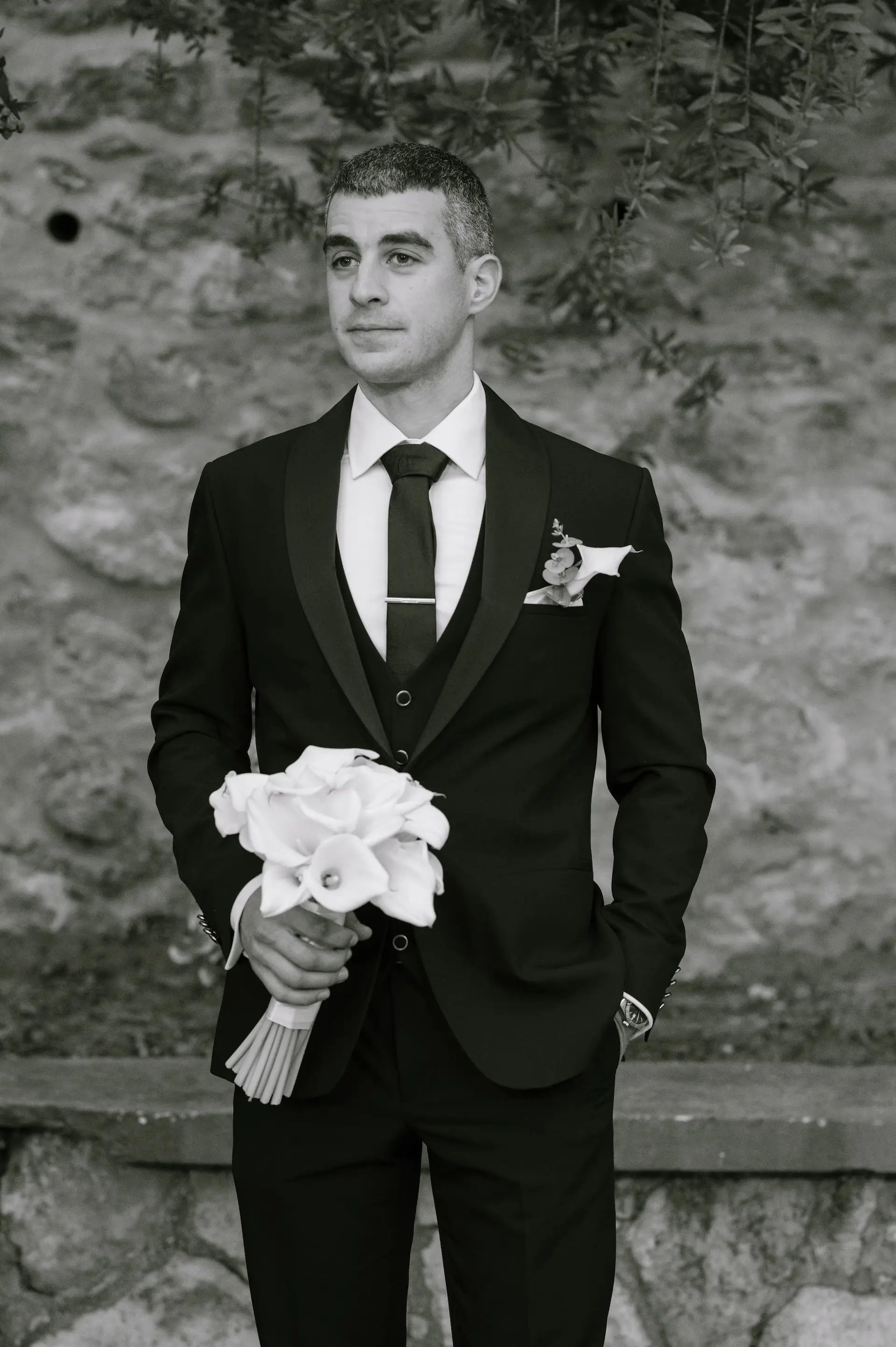 groom portrait in black and white holding wedding flowers