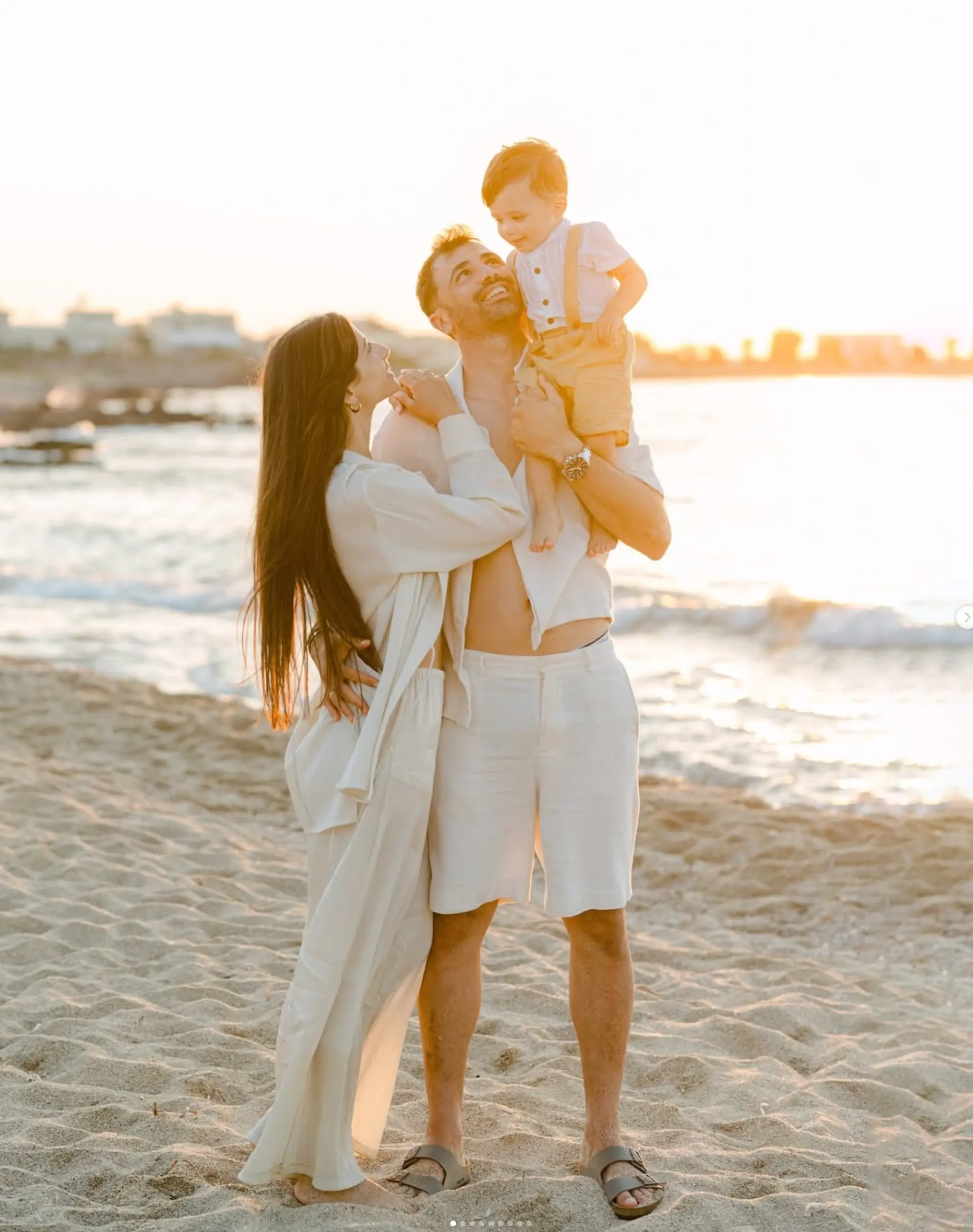 a man and woman holding a baby on a beach