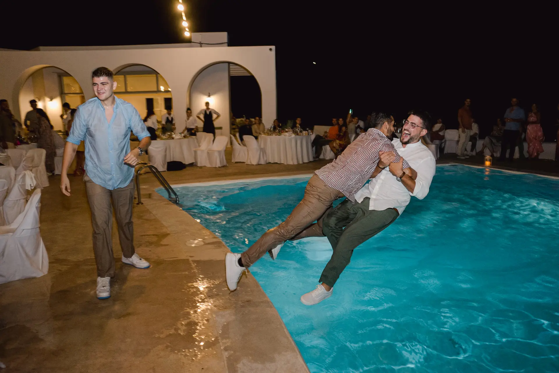 a group of men jumping into a pool