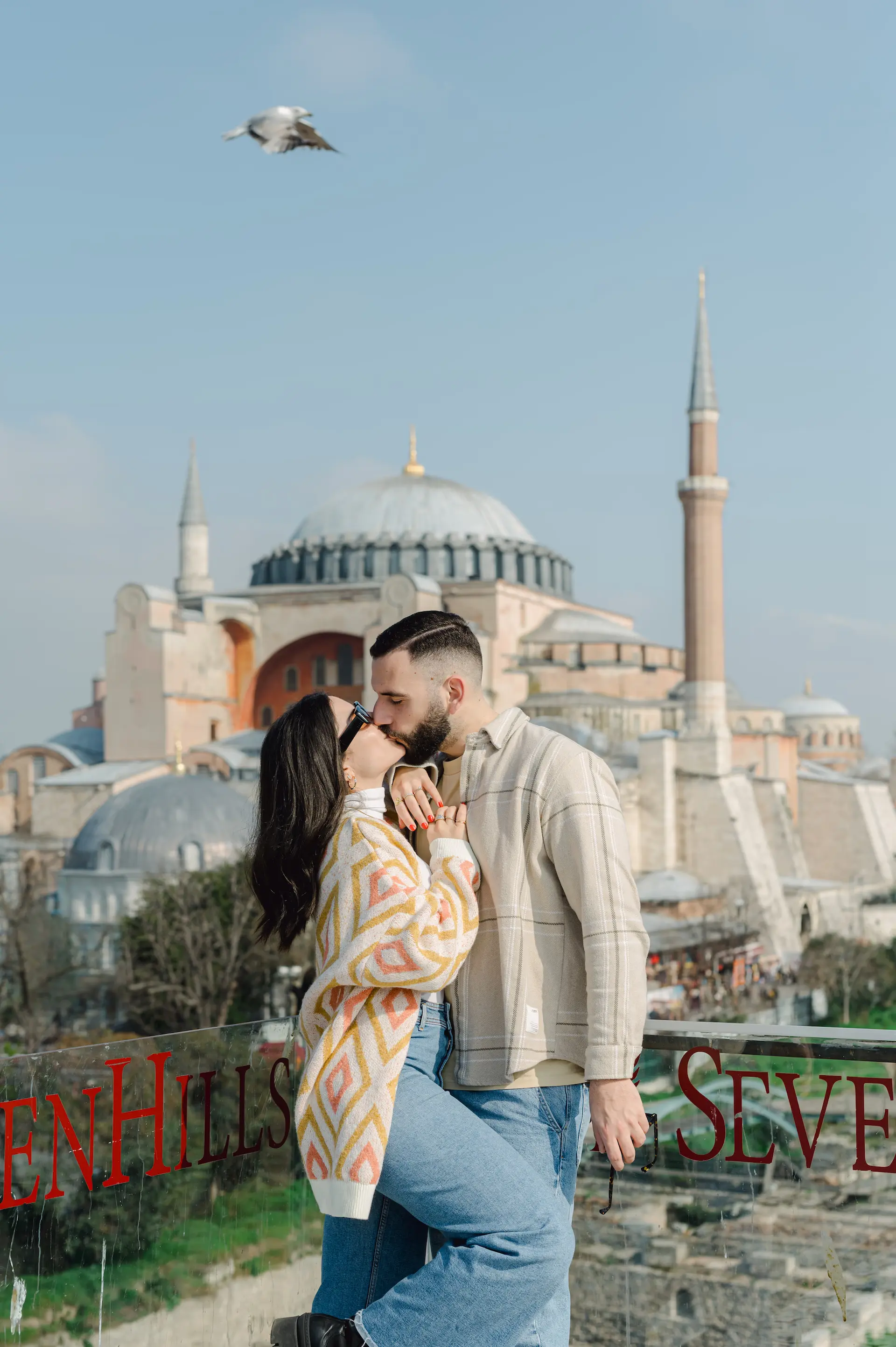 a man and woman kissing in front of a large building with Hagia Sophia in the background