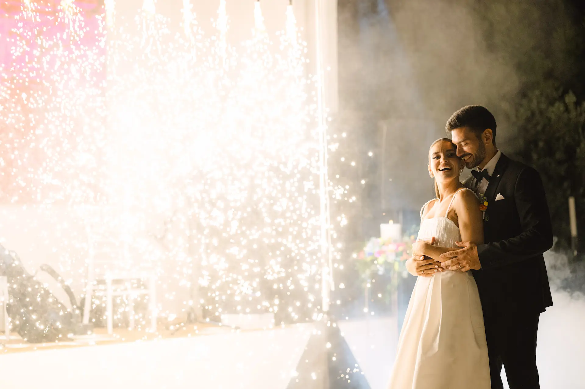 a man and woman hugging in front of fireworks