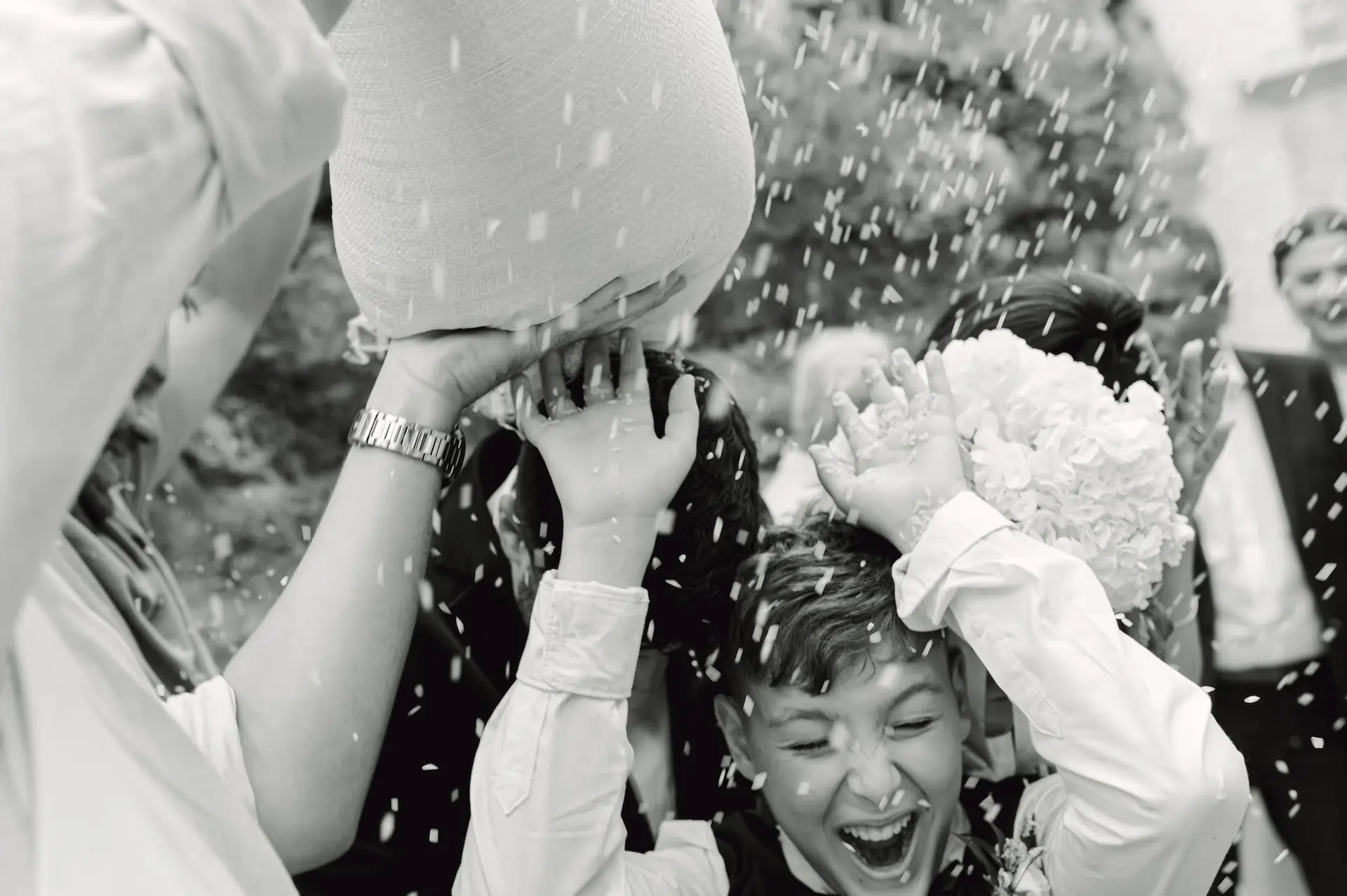 Candid shot of wedding guests throwing rice at the newlyweds, capturing a high-energy emotional momenta group of people throwing pillows into each other