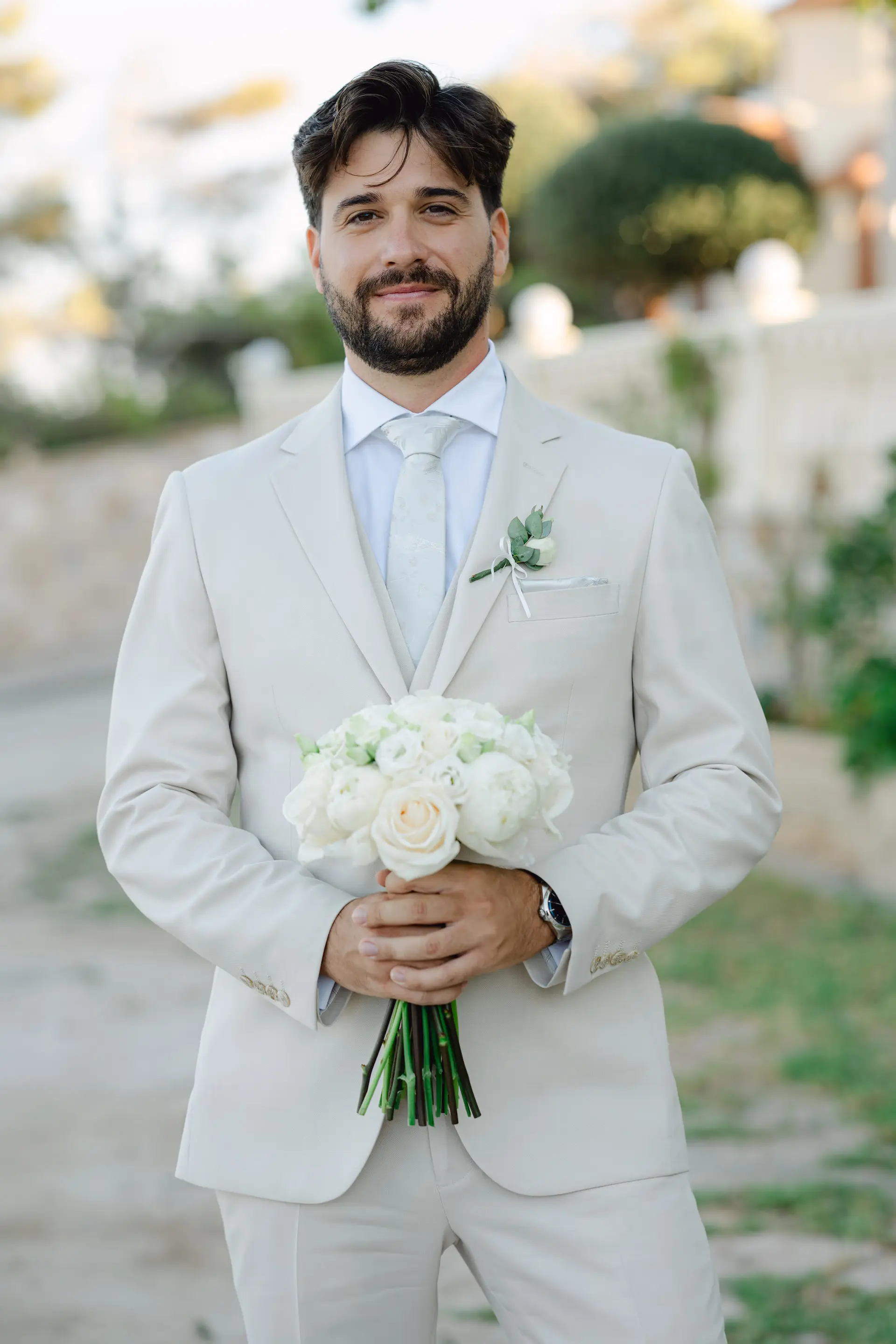 Groom holding the wedding bouquet while waiting for the bride at the ceremony