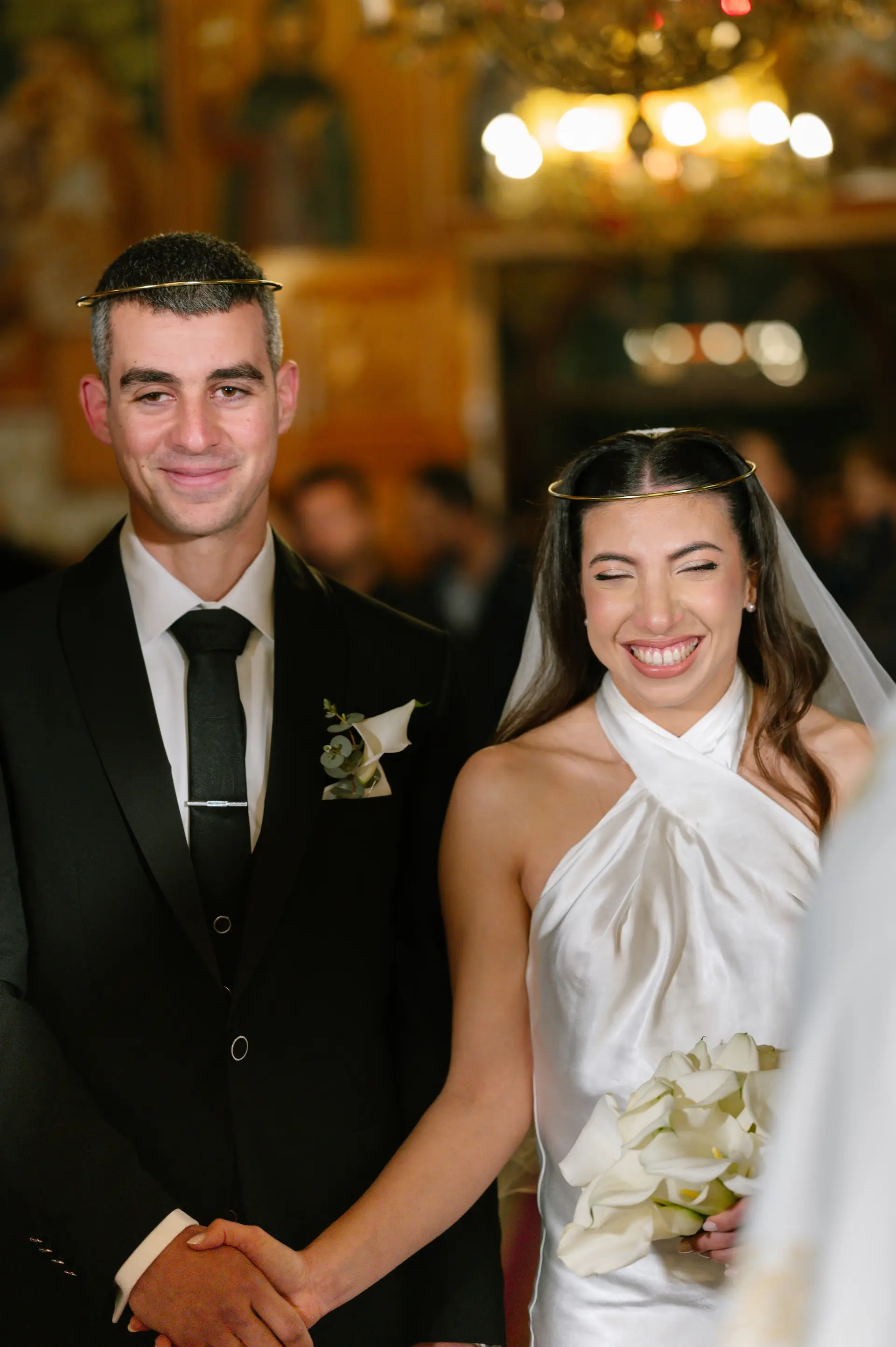 portrait of bride and groom smiling and holding hands inside the church