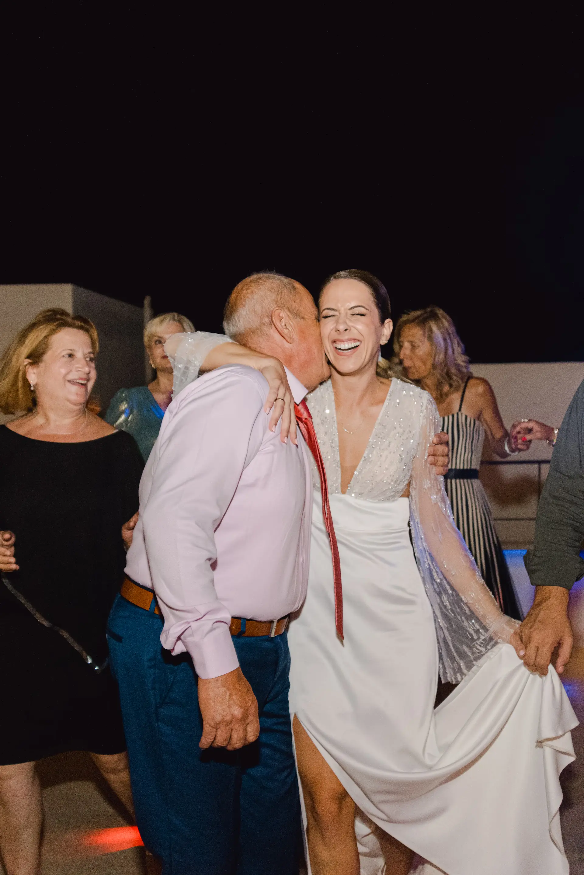 Emotional moment of a father kissing the bride during a traditional wedding dance.
