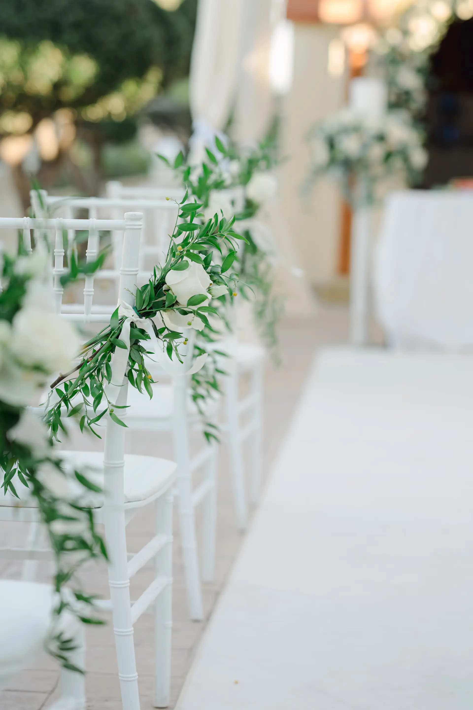 Minimalist wedding ceremony decor featuring white floral arrangements and wooden chairs