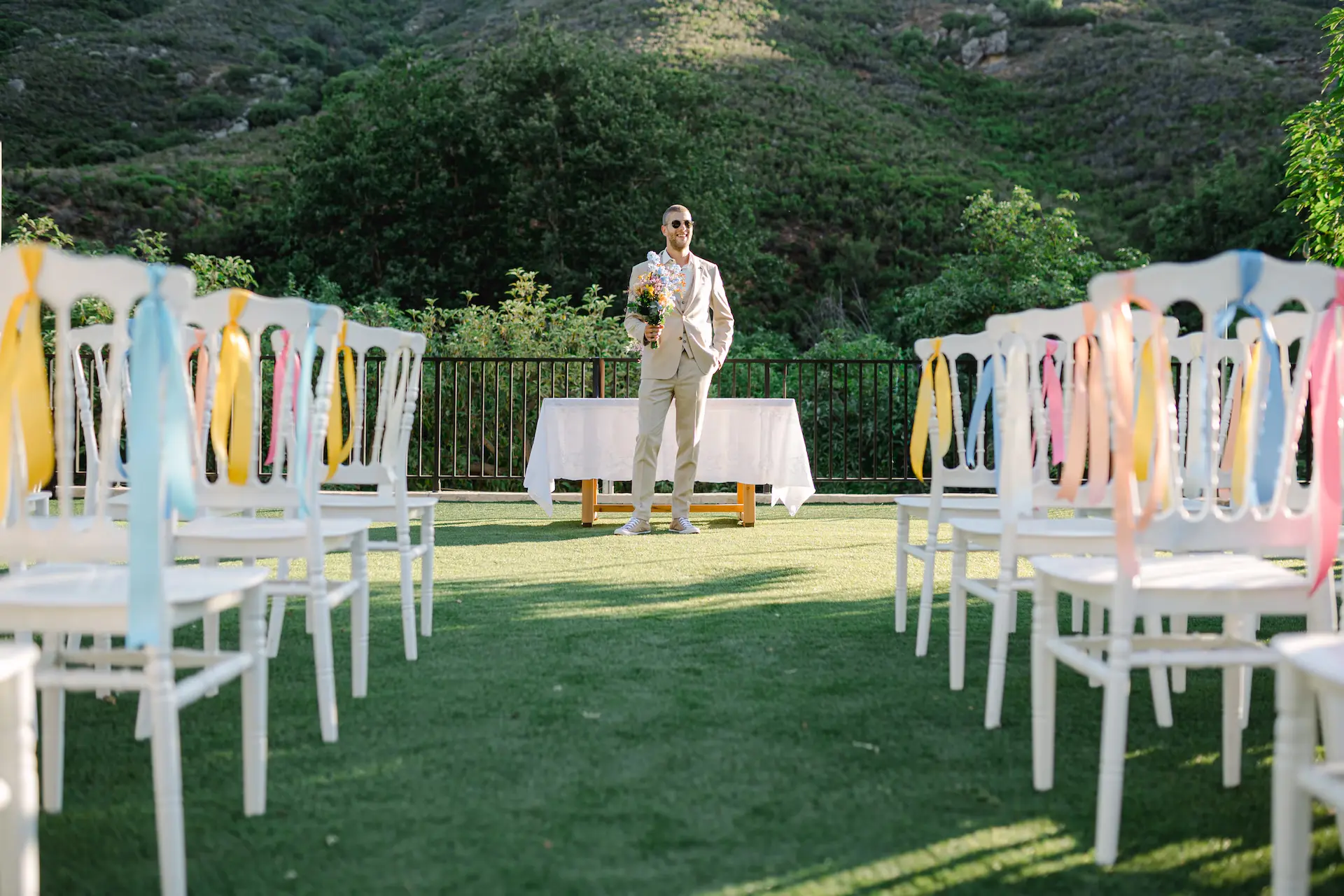groom standing in front of the wedding chairs