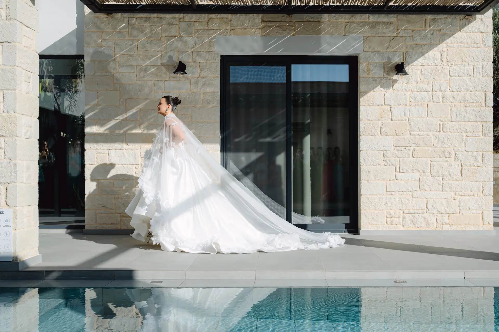 Stunning bride walking by a swimming pool, capturing the reflection and the elegant movement of the wedding dress.