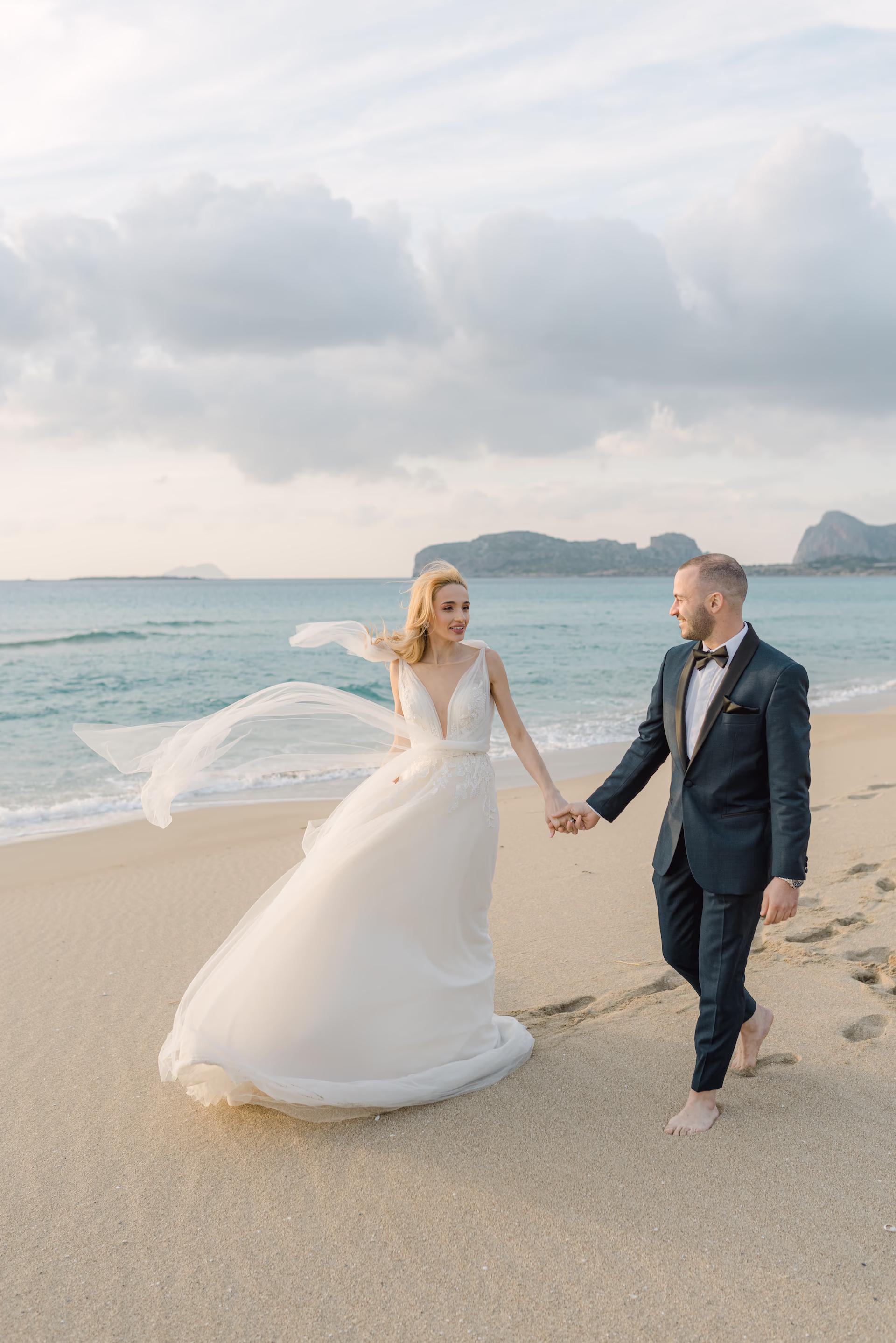 bride and groom holding hands on a beach in chania