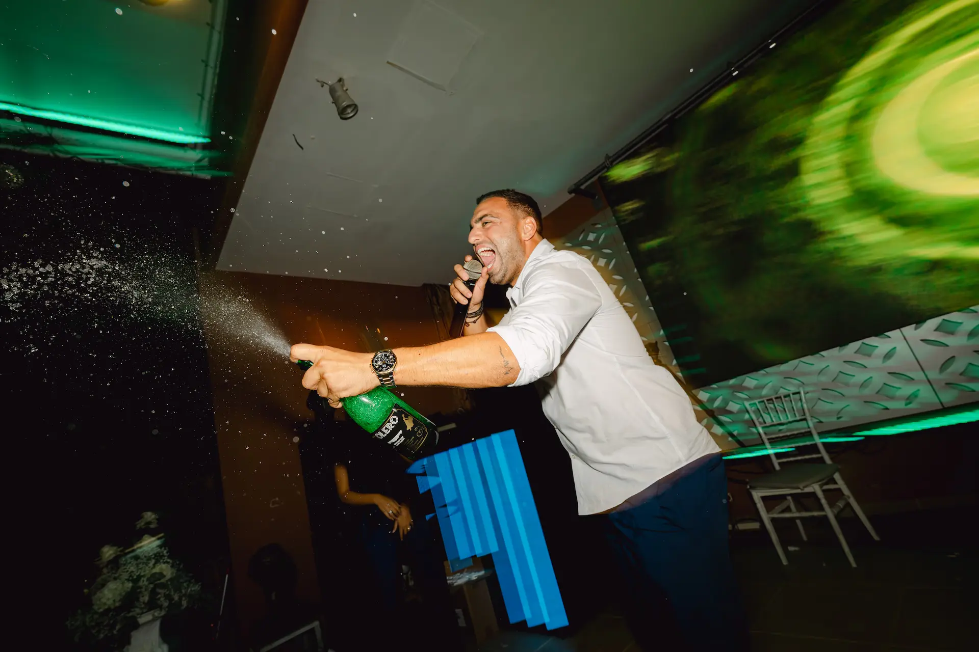 a man holding a bottle of champagne pouring it 
