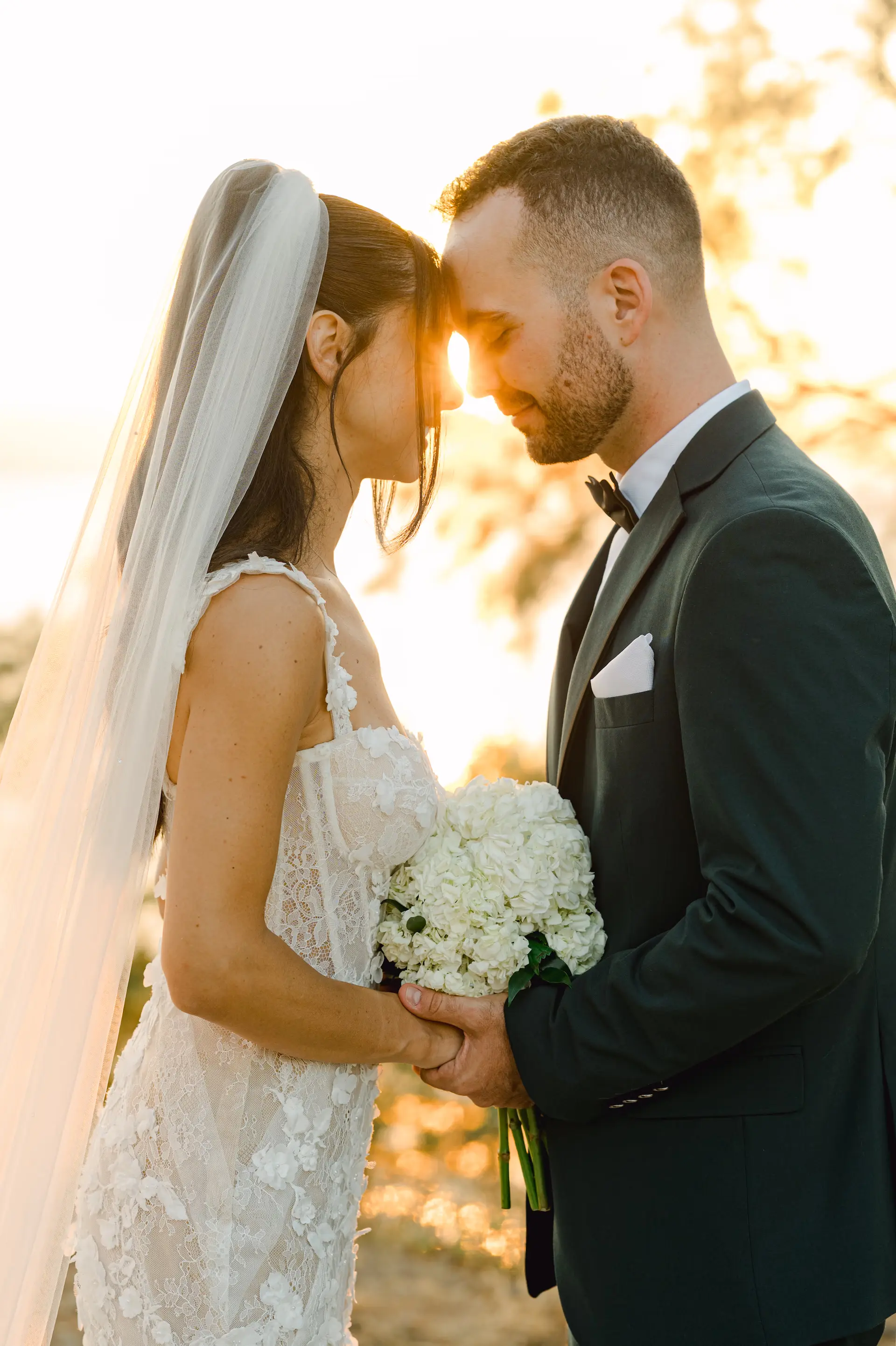 Candid wedding photography capturing a close, authentic moment of a couple holding flowers.