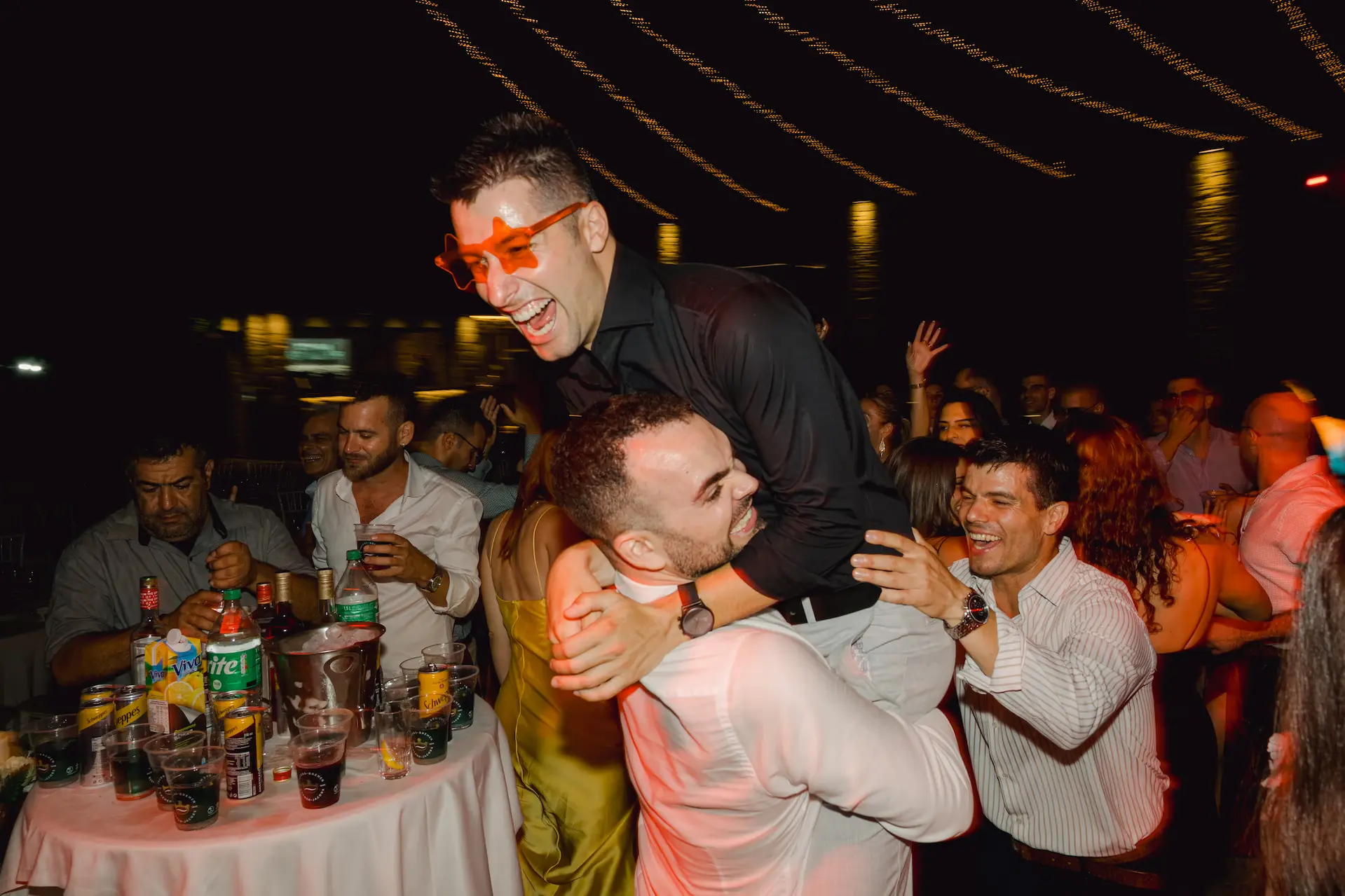 groom carrying bestman in a crowd of people in the dancefloor
