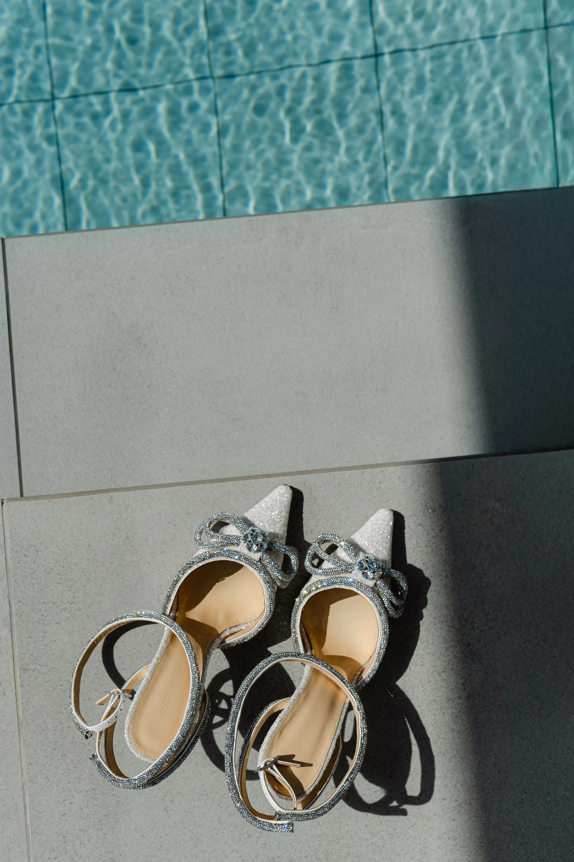 a pair of wedding high heeled shoes by a pool
