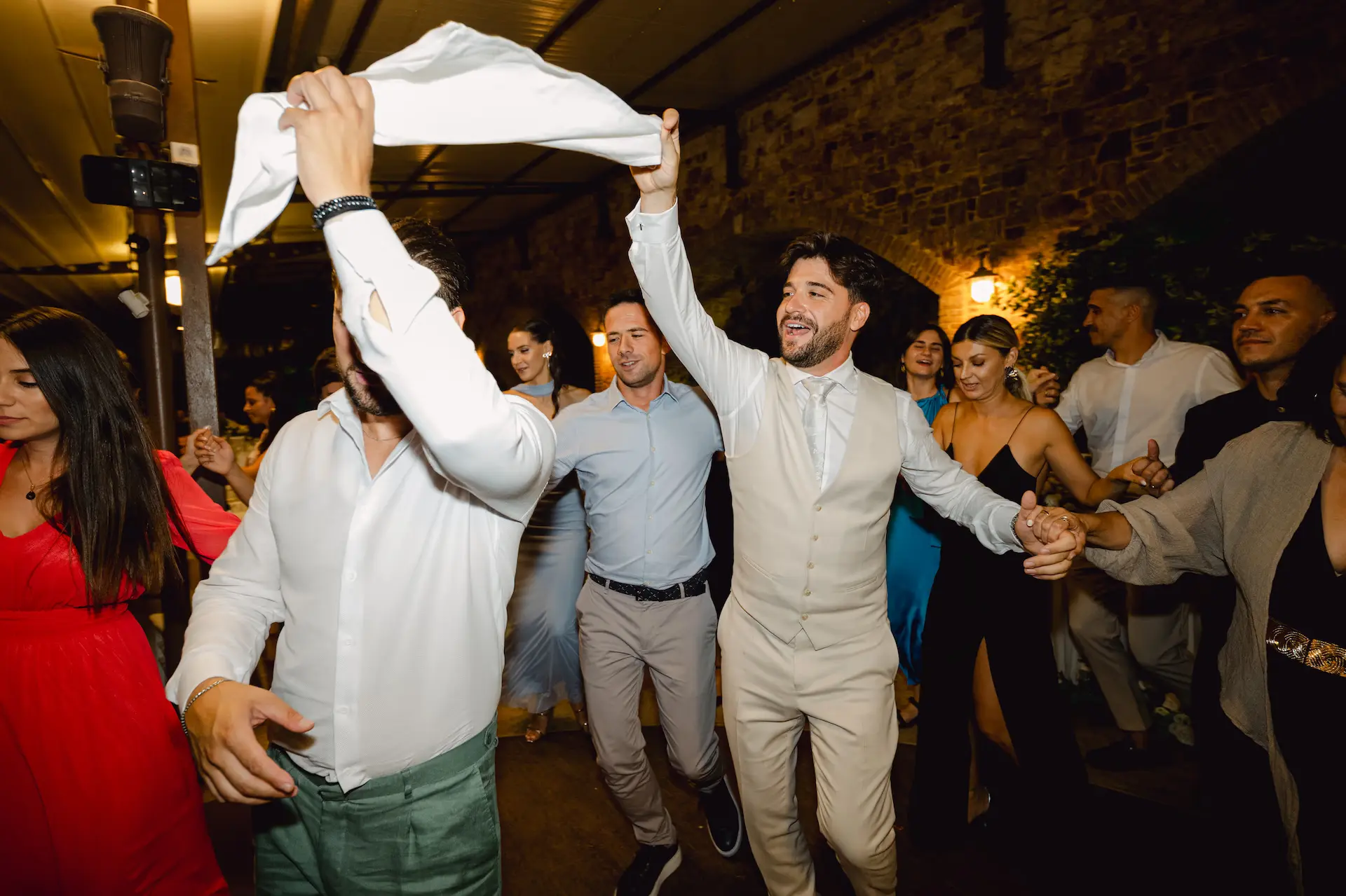 Dynamic shot of the wedding party joining in a traditional circle dance on the dance floor