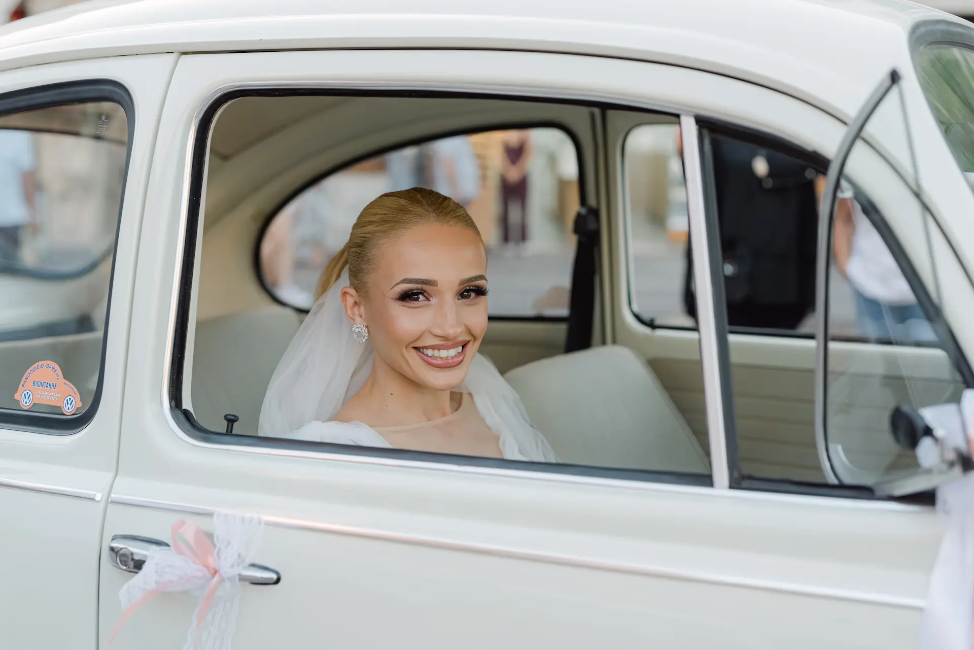 Candid shot of the smiling bride inside a vintage car arriving at the church.