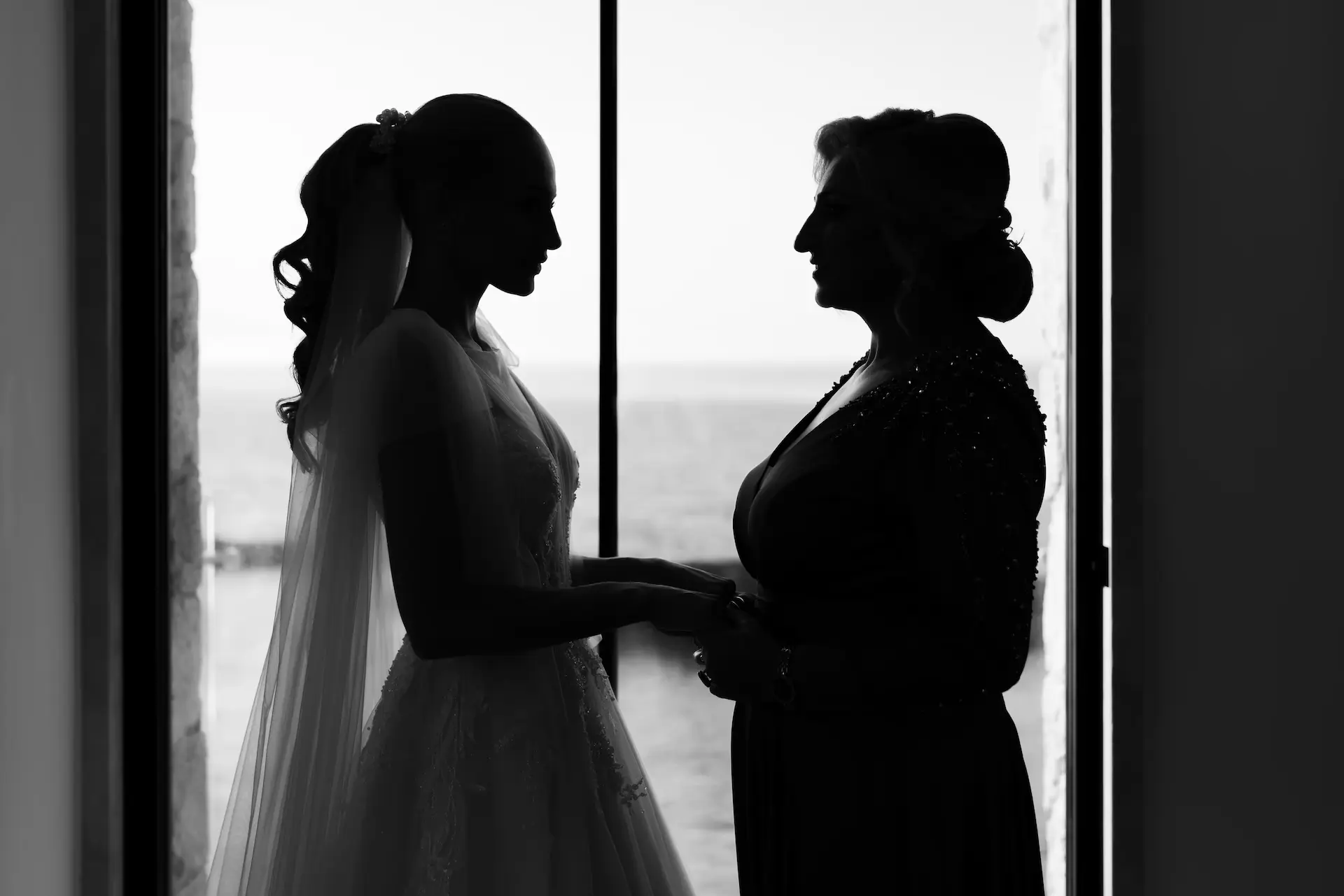 a silhouette of the bride holding hands with her mother