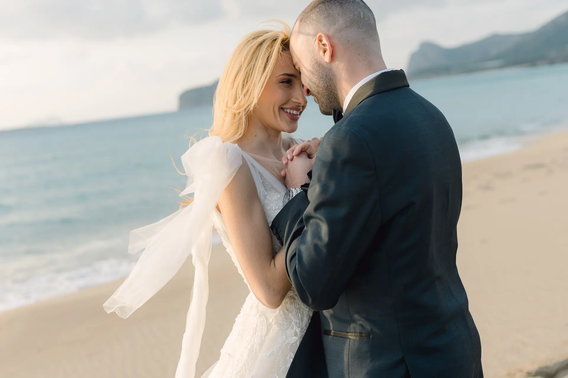 Close-up of a man and woman holding hands while walking on the beach.