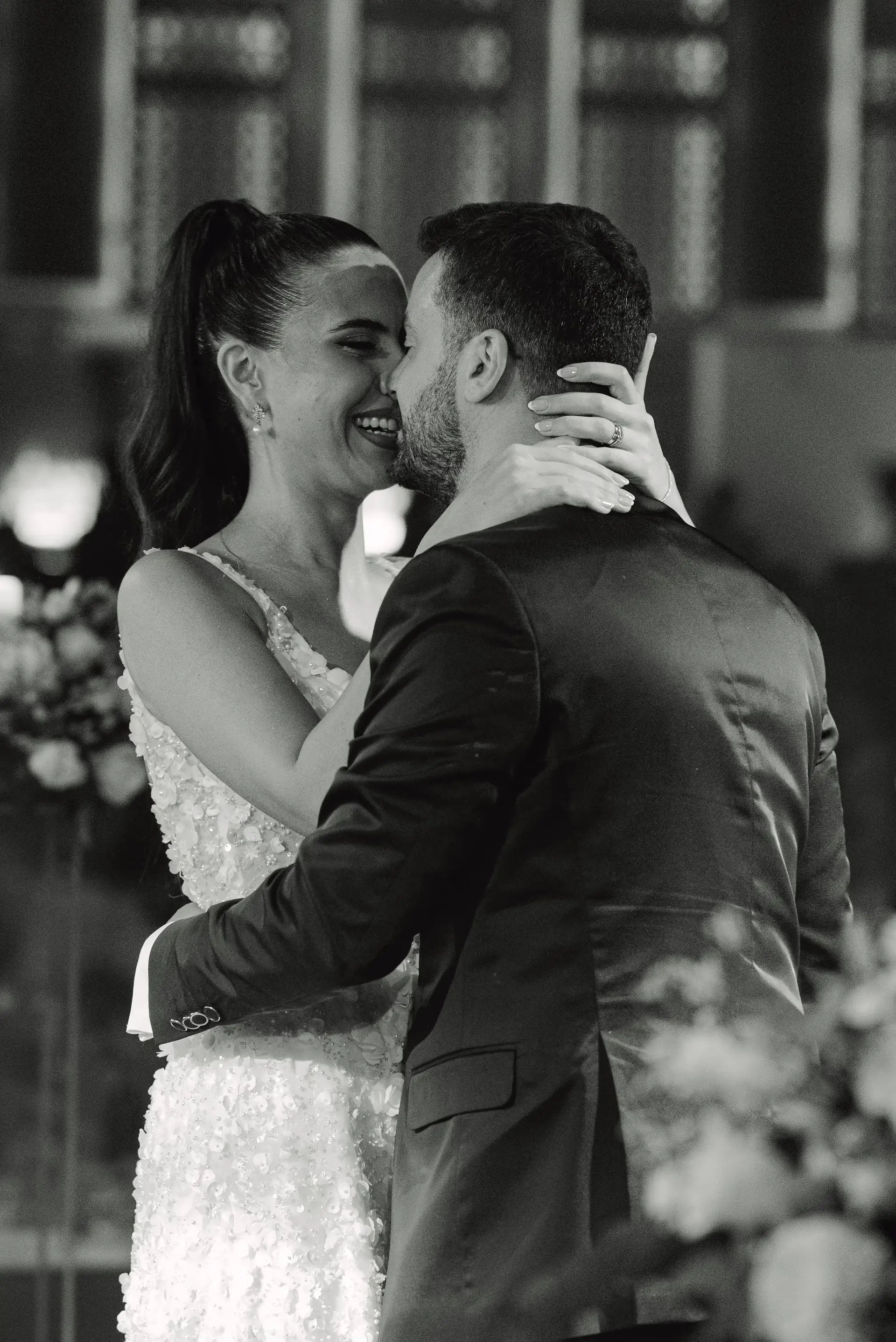Romantic wedding couple sharing a kiss during their first dance under ambient reception lighting.