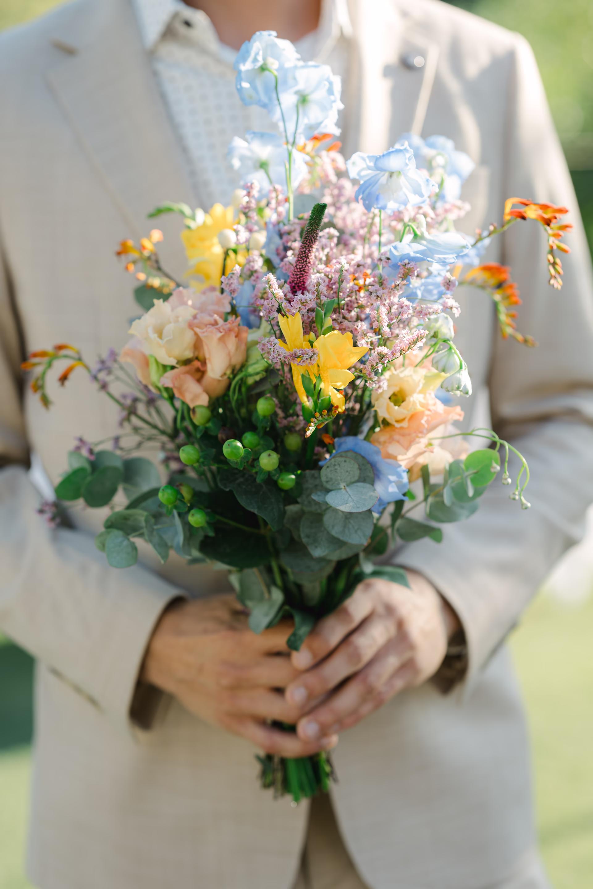 Vibrant wedding bouquet with coral sunset peonies, ranunculus, and garden roses.