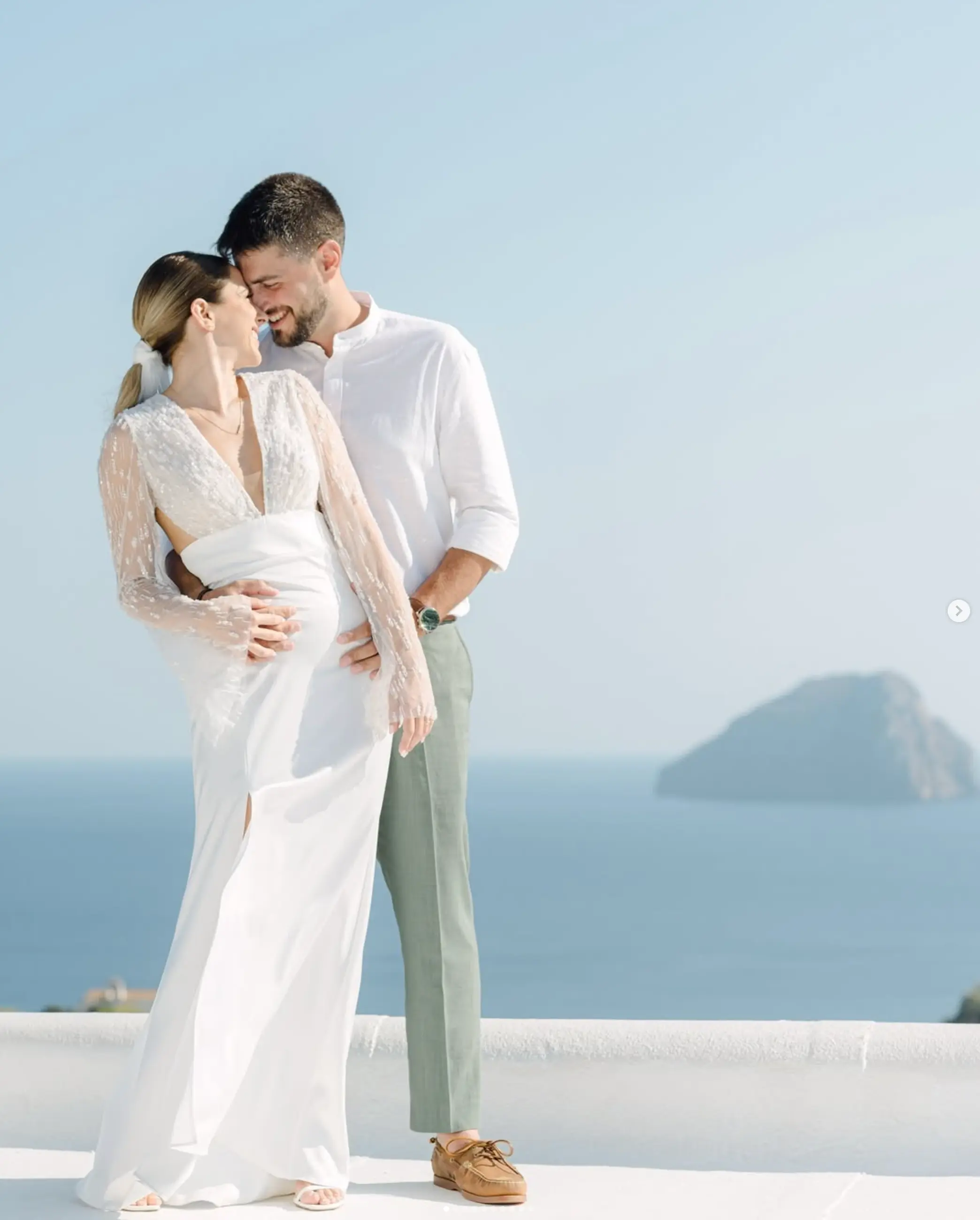 a man and woman standing on a balcony with water in the background