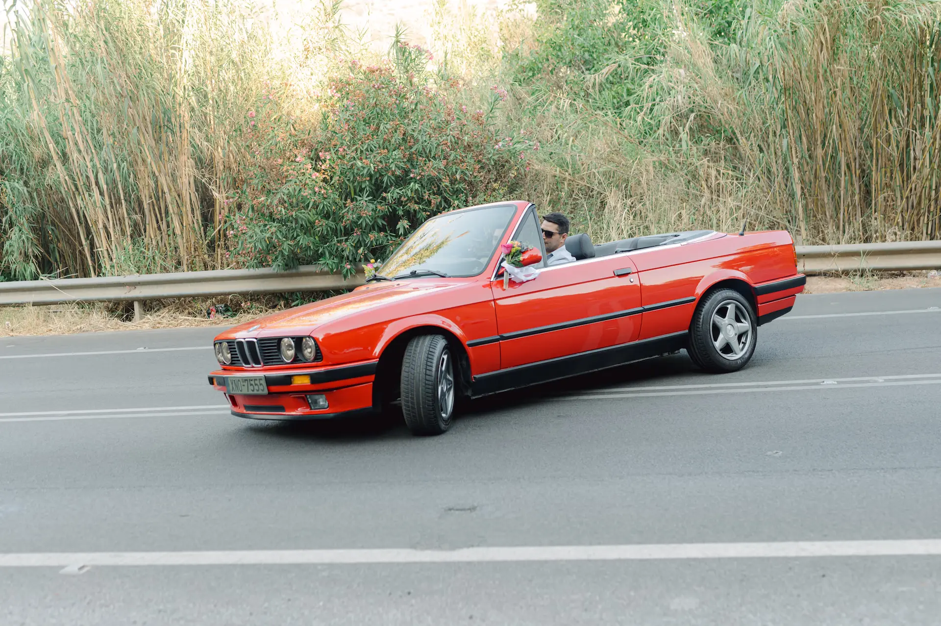 a red convertible car with a man in the back