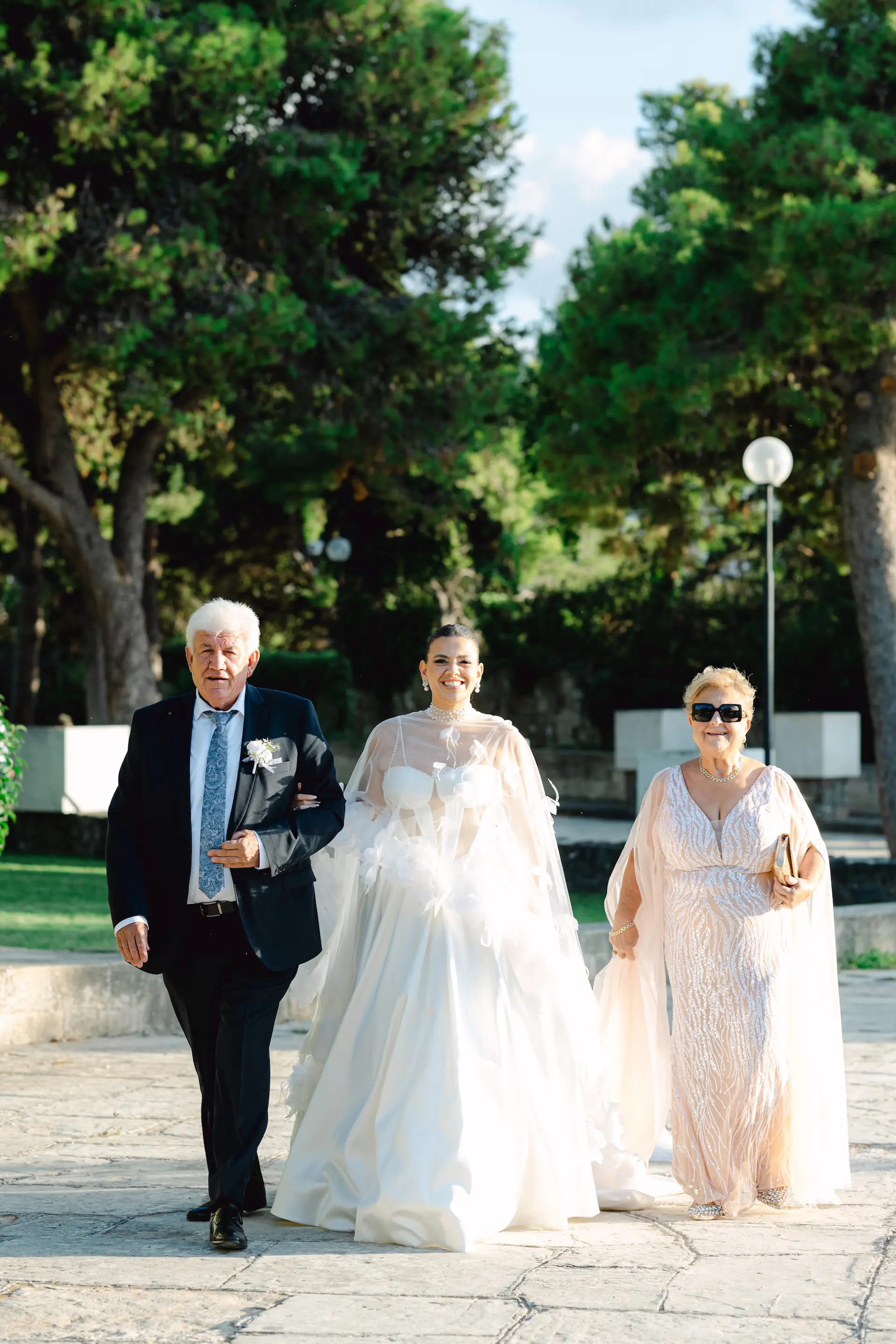 Emotional moment of the bride walking to the church accompanied by her parents in a traditional Chania wedding.
