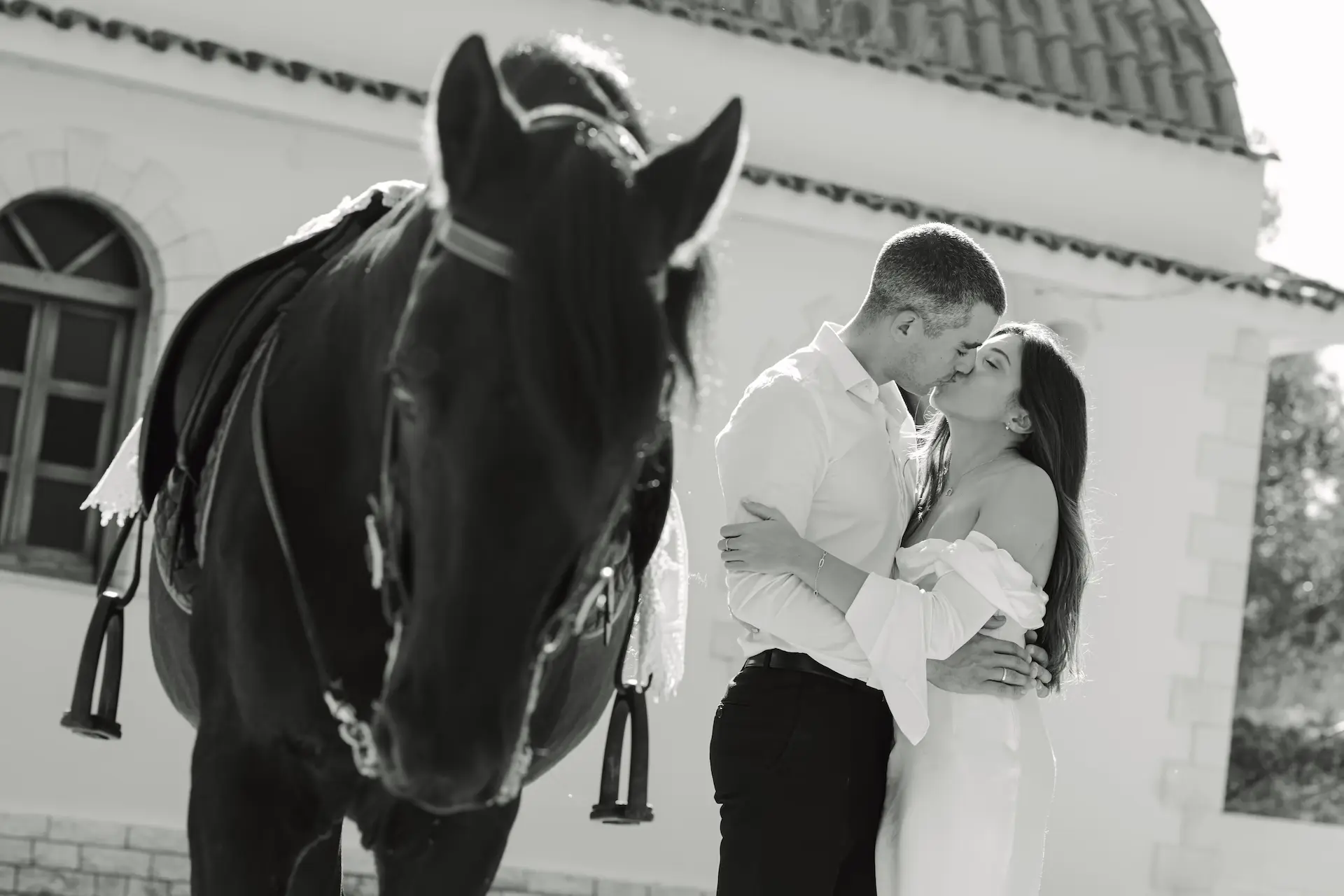 Romantic moment with the bride and groom kissing next to a beautiful horse.