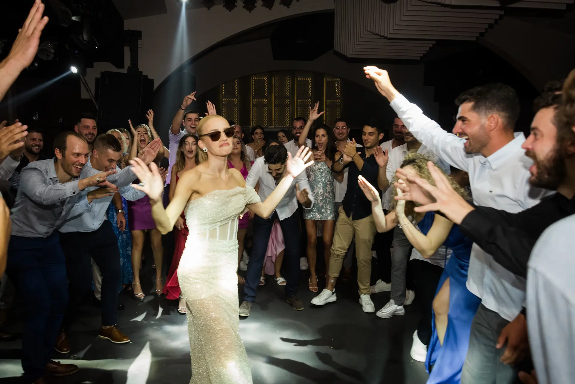 Bride dancing in the center of the dance floor surrounded by cheering guests during the wedding party.