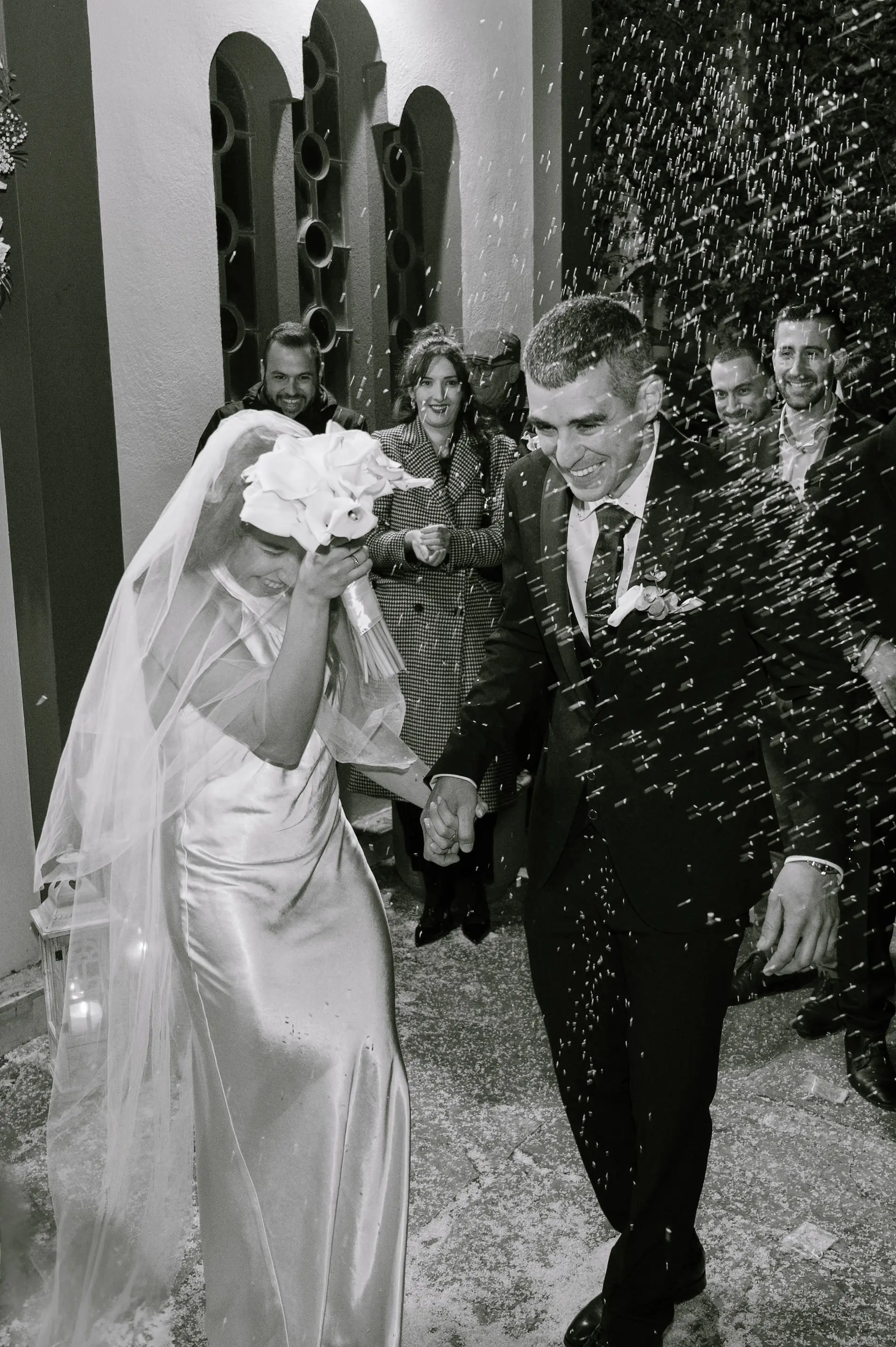 a bride and groom laughing as the guests throwing rice