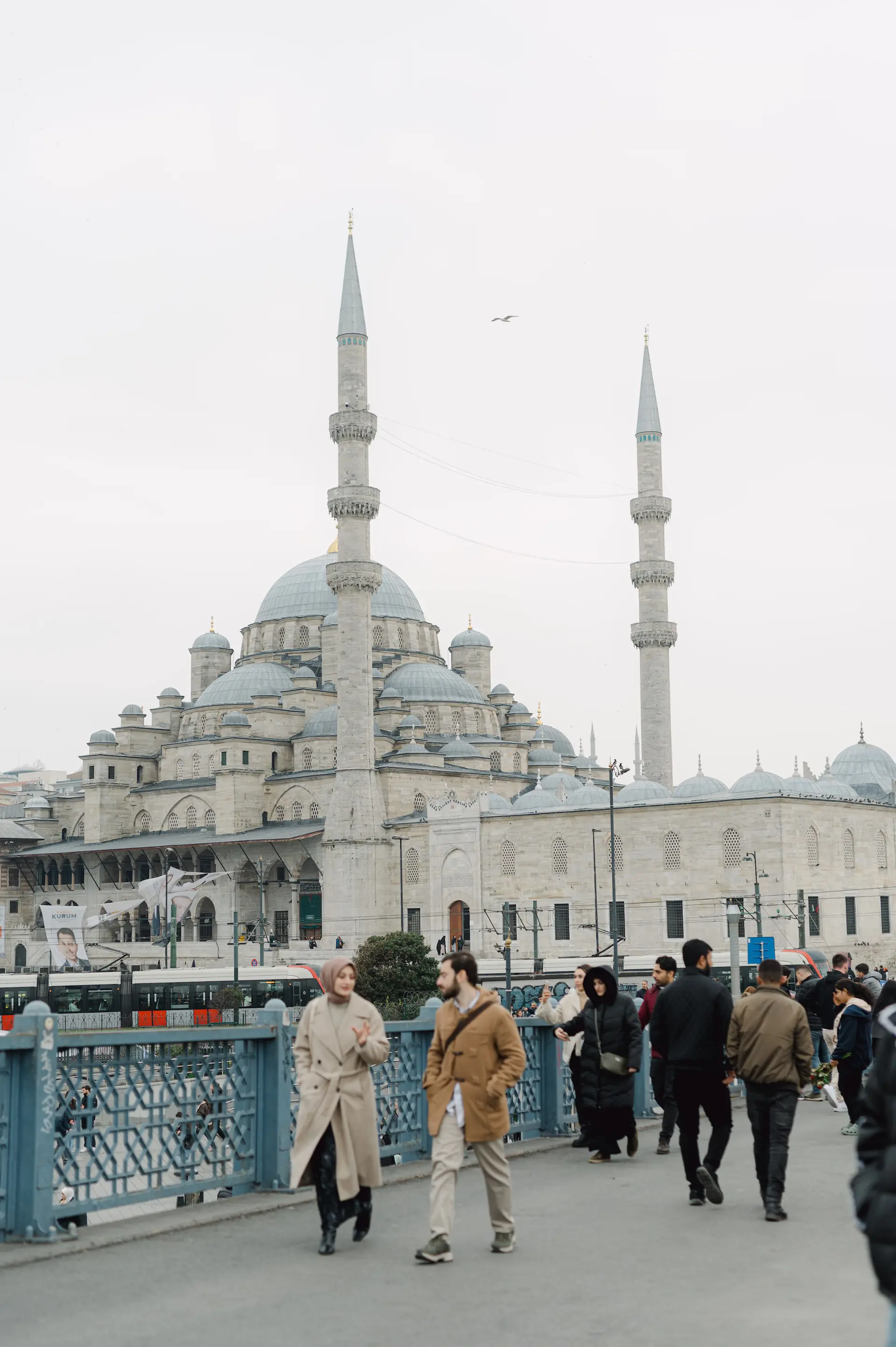 a group of people walking in front of a large building with New Mosque in the background