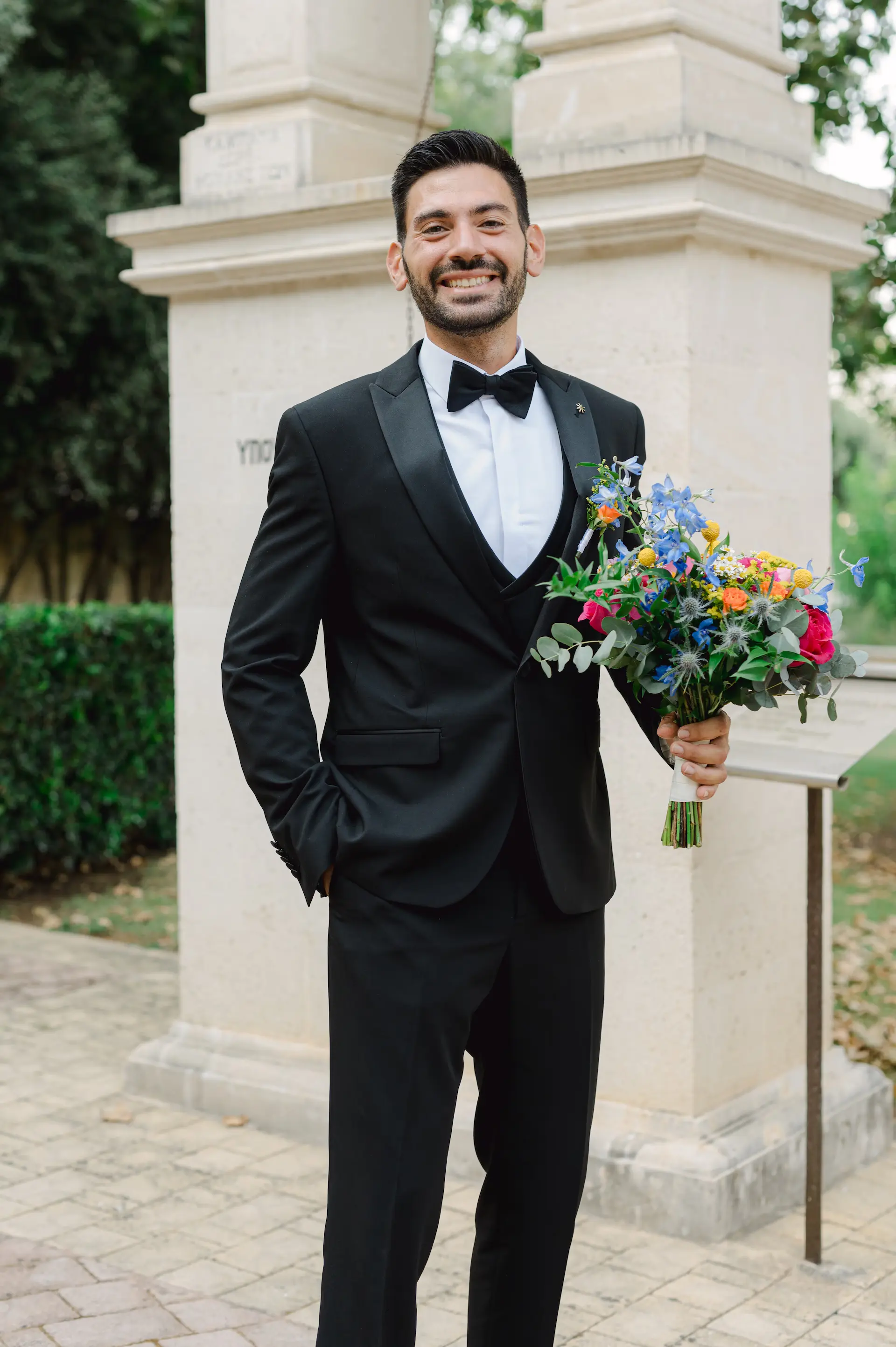 a man in a tuxedo holding flowers