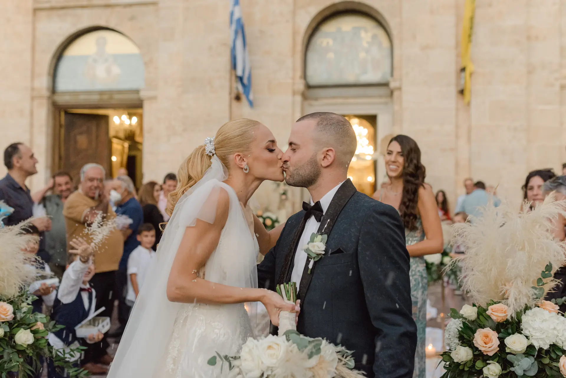 Romantic moment of the bride and groom kissing in front of their cheering guests.