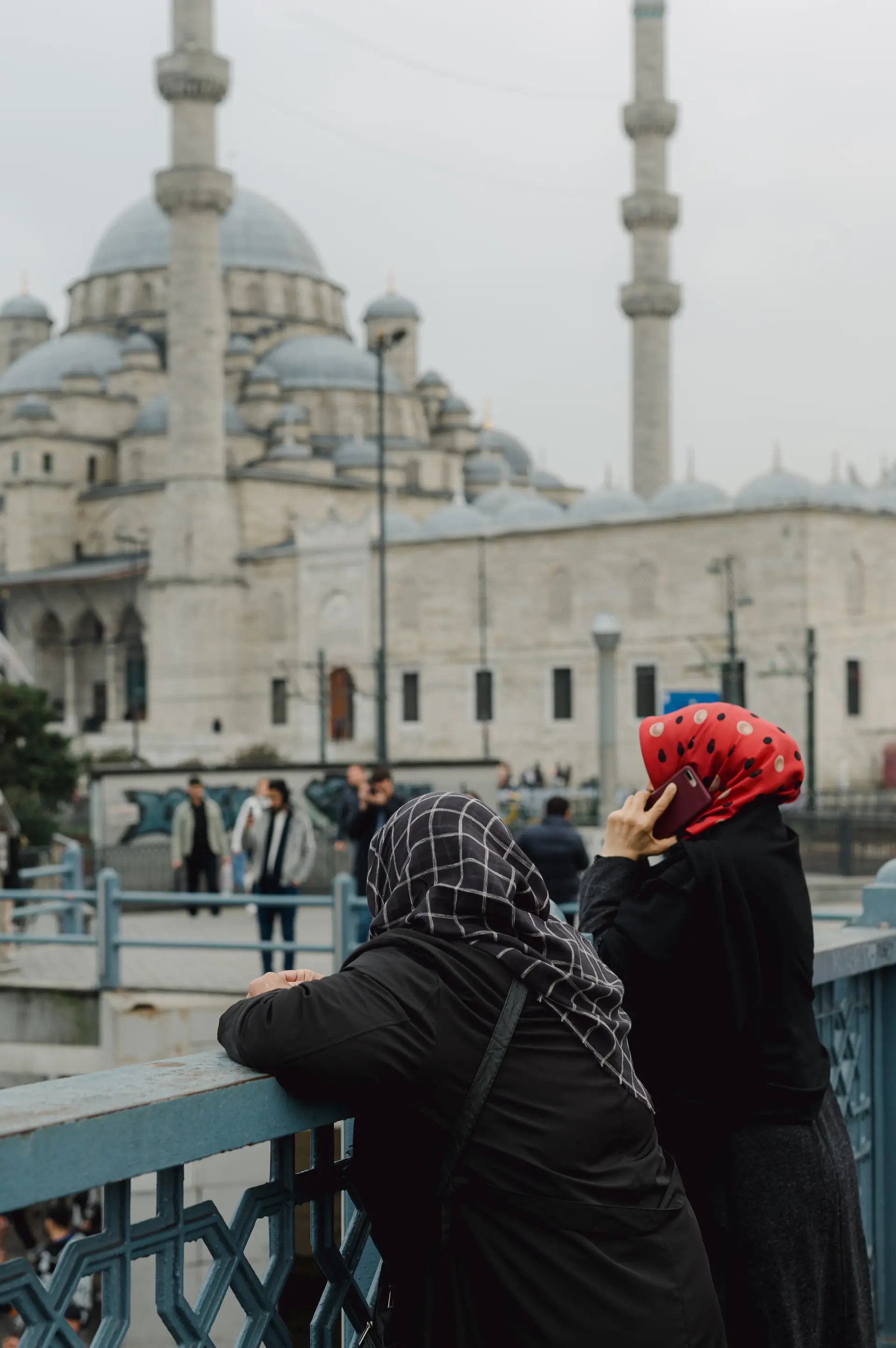 a woman in a headscarf on a bridge with a building in the background