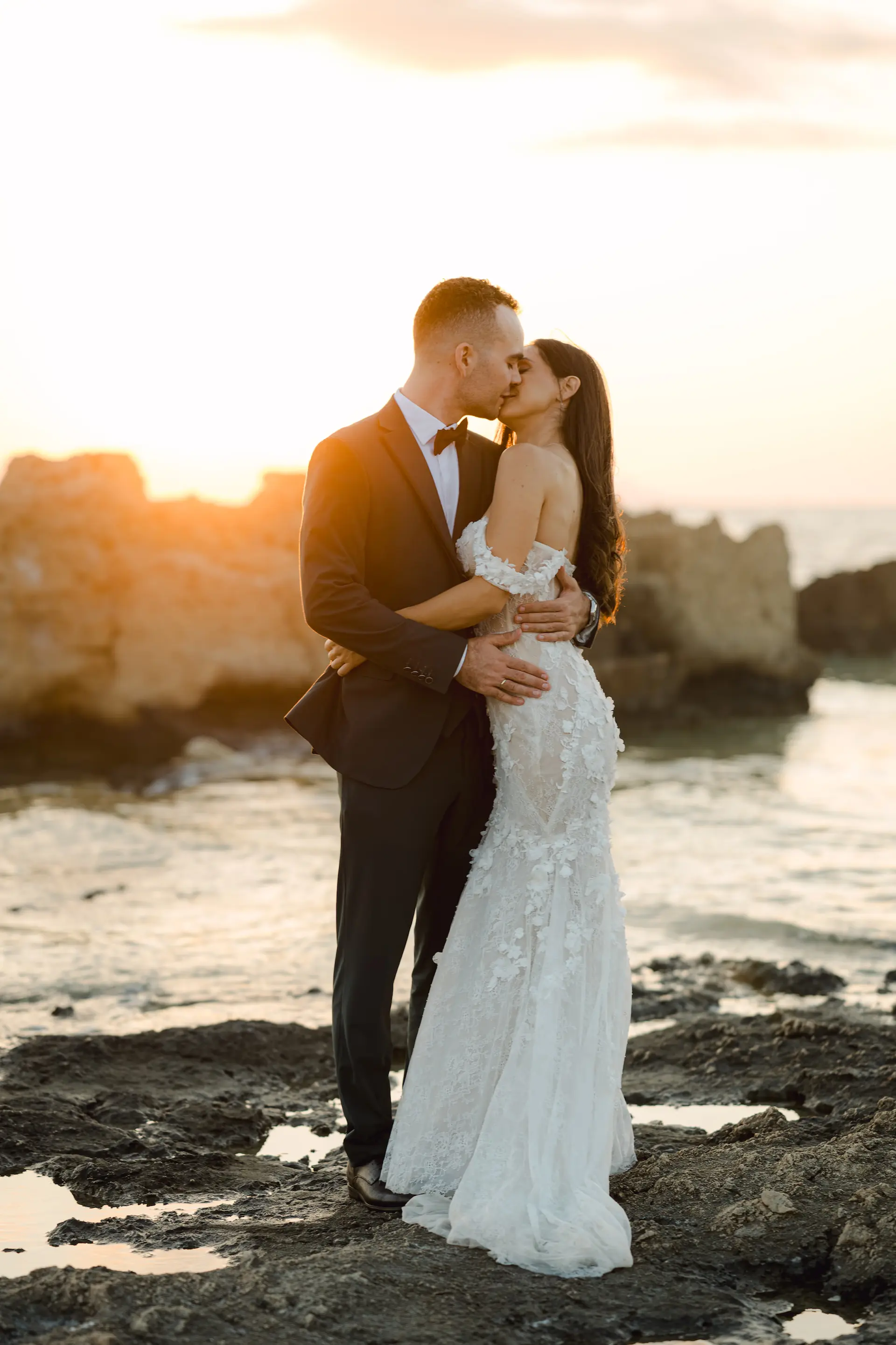 Portrait of a bride and groom kissing on the beach of Stavros during a golden sunset.