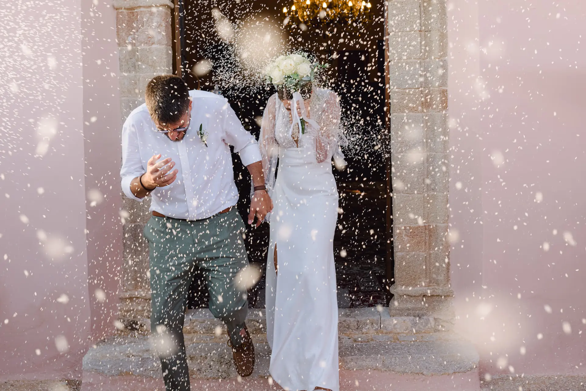 Newlyweds laughing during the traditional rice toss as they exit the church ceremony.
