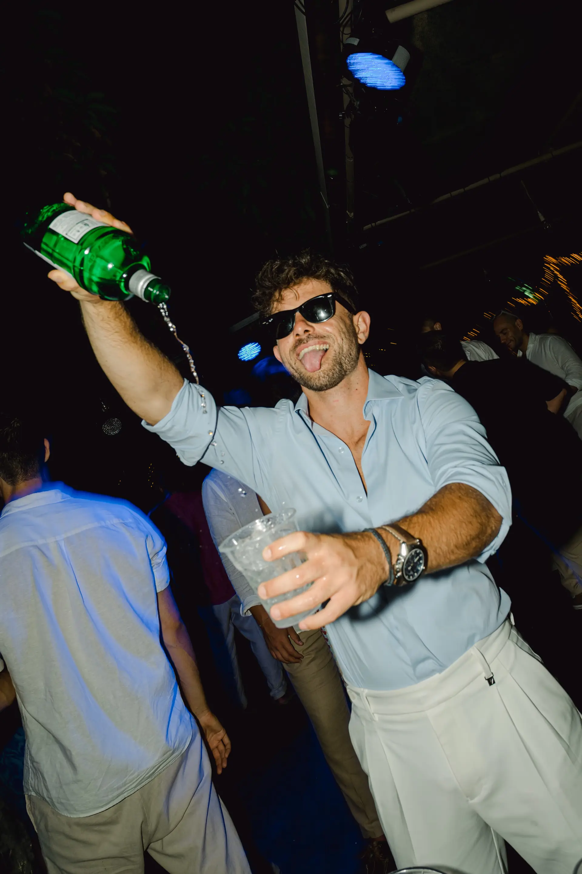 best man pouring a drink into a cup wearing sunglasses