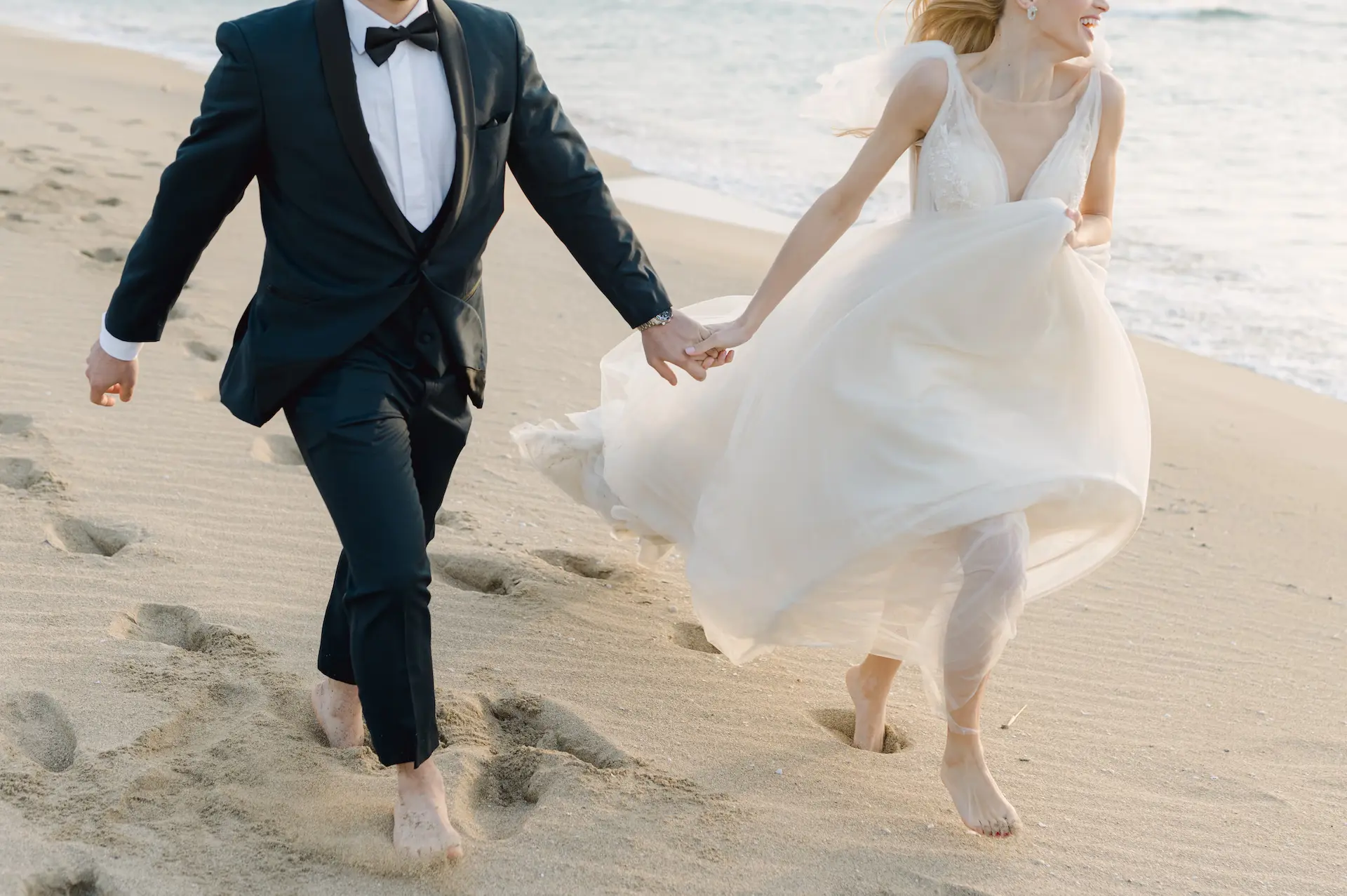 Joyful bride and groom running freely along the shore of Falasarna beach.