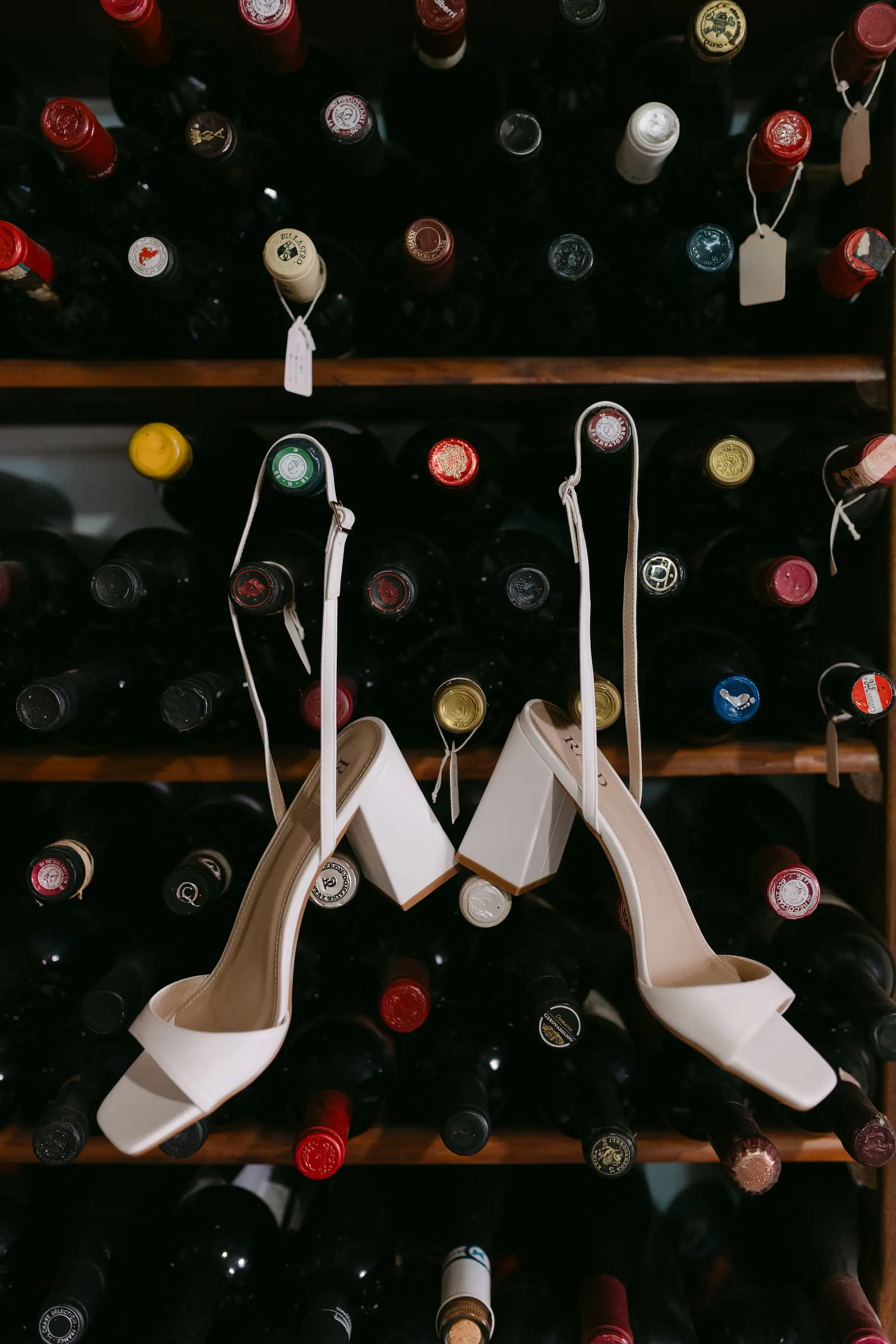 bride's shoes from a rack of wine bottles